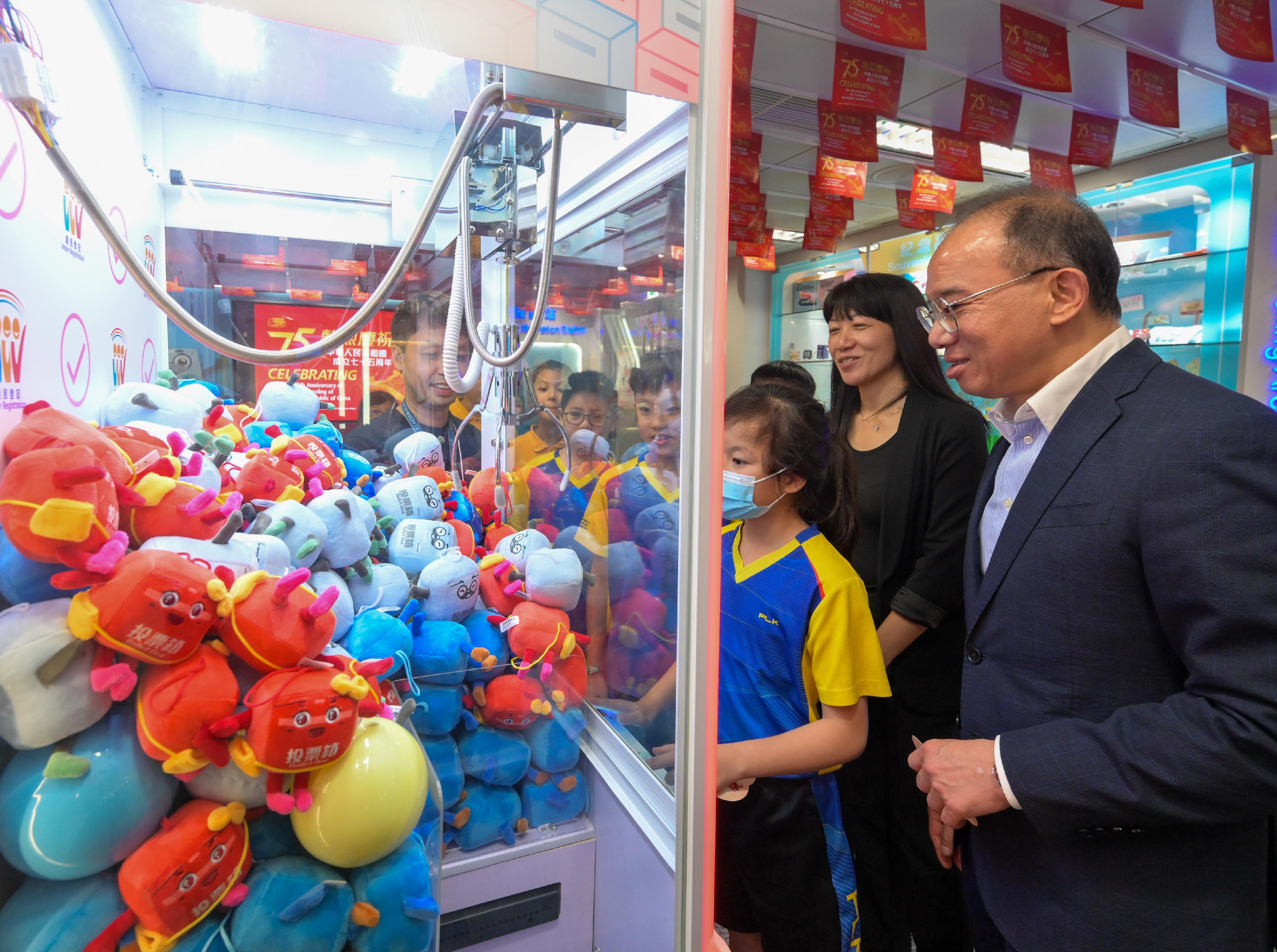 To celebrate the 75th anniversary of the founding of the People's Republic of China, the Electoral Information Centre of the Registration and Electoral Office (REO) is holding National Day Open Days for three consecutive days from today (September 30). The Secretary for Constitutional and Mainland Affairs, Mr Erick Tsang Kwok-wai, attended a guided tour for a group of senior primary school students this afternoon. Photo shows Mr Tsang (first right), and the Chief Electoral Officer of the REO, Ms Natalie Chan (second right), trying their hand at the claw game machine with the students. 