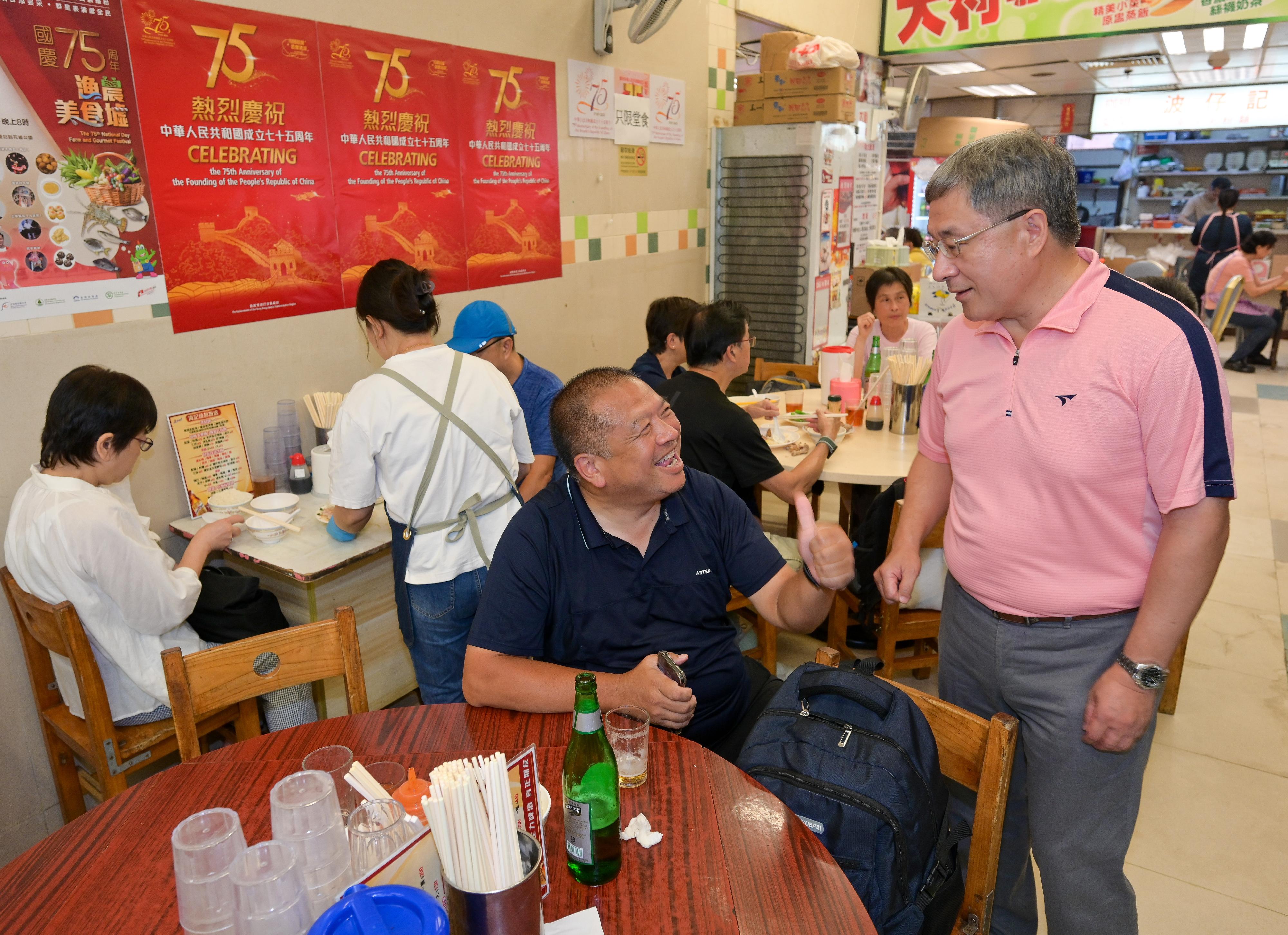 The Deputy Chief Secretary for Administration, Mr Cheuk Wing-hing (right), chats with members of the public enjoying dining discounts to celebrate the 75th anniversary of the founding of the People's Republic of China at  the Wan Chai Bowrington Road Cooked Food Centre today (October 1).