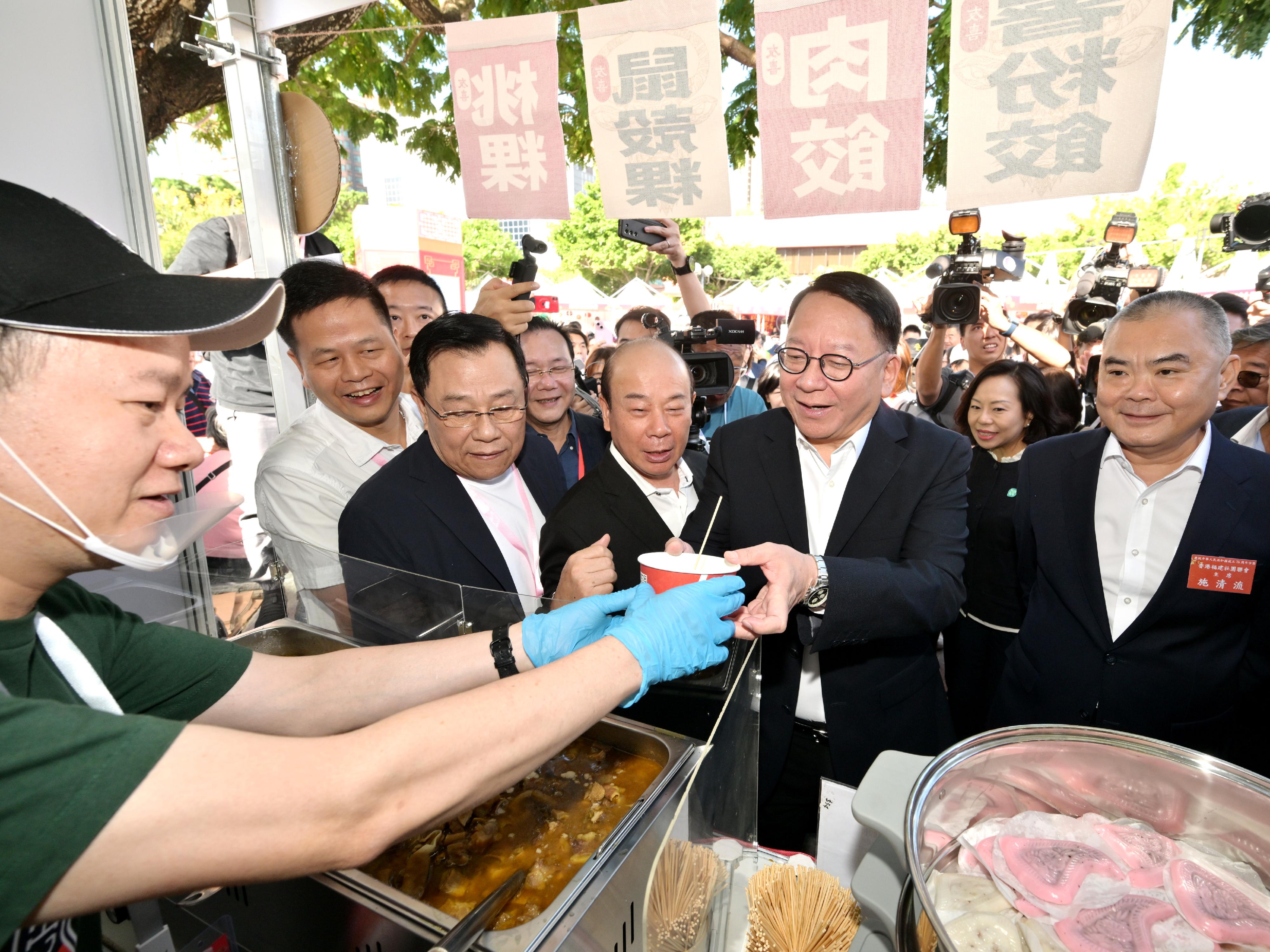 The Chief Secretary for Administration, Mr Chan Kwok-ki, attended the opening ceremony of the Bazaar Carnival in Celebration of the 75th Anniversary of the Founding of the People's Republic of China today (October 25). Photo shows Mr Chan (third right), accompanied by the Chairman of the Federation of Hong Kong Guangdong Community Organisations, Mr Kung Chun-lung (fourth right); the Chairman of the Hong Kong Federation of Fujian Associations, Mr Sze Ching-lau (first right); and the Secretary for Home and Youth Affairs, Miss Alice Mak (second right), visiting a booth of the Bazaar Carnival.