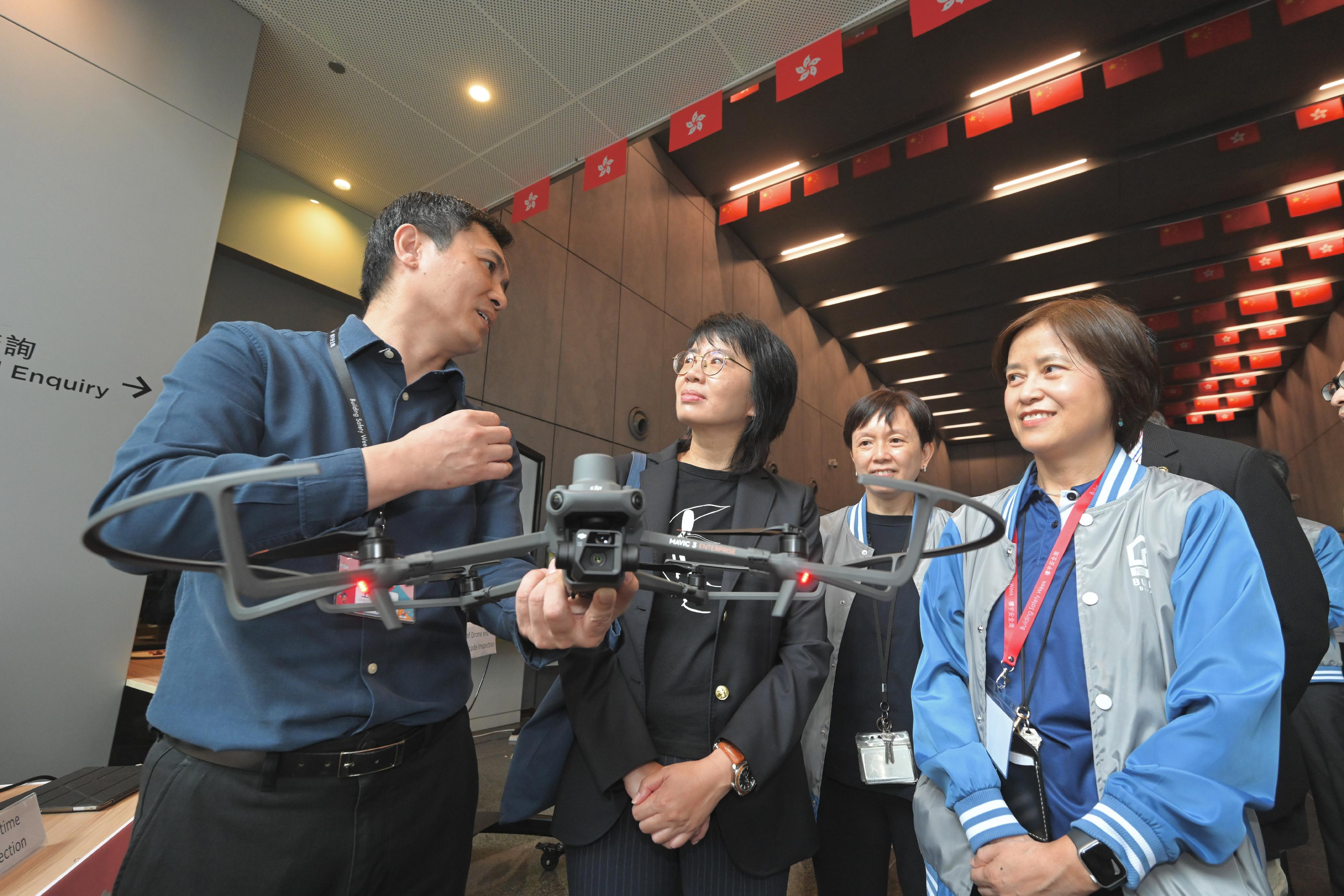 The Buildings Department (BD) launched Building Safety Weeks 2024 today (October 26). Photo shows the Permanent Secretary for Development (Planning and Lands), Ms Doris Ho (second left), accompanied by the Director of Buildings, Ms Clarice Yu (first right), being briefed on the use of drones and artificial intelligence to assist in external wall inspections of old buildings at the BD Inno Tech Open Day held at the BD headquarters.