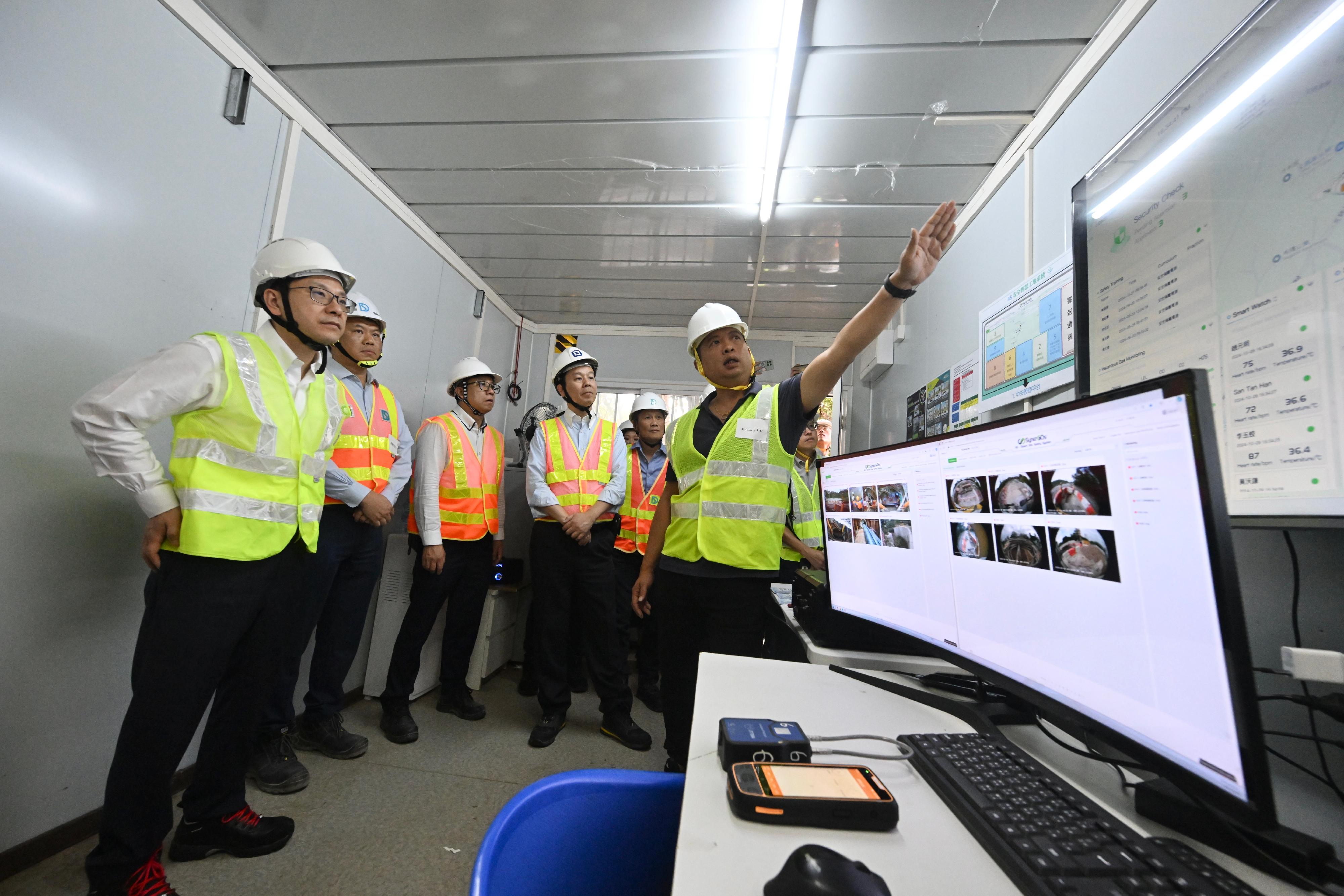 The Secretary for Labour and Welfare, Mr Chris Sun, visited a construction site today (October 28) to call on contractors, employers and workers to pay attention to work safety and health in confined space workplaces. Photo shows a representative of the contractor briefing Mr Sun (first left) and the Deputy Commissioner for Labour (Occupational Safety and Health), Mr Vincent Fung (fourth left), on relevant measures of the Smart Site Safety System implemented at the site.