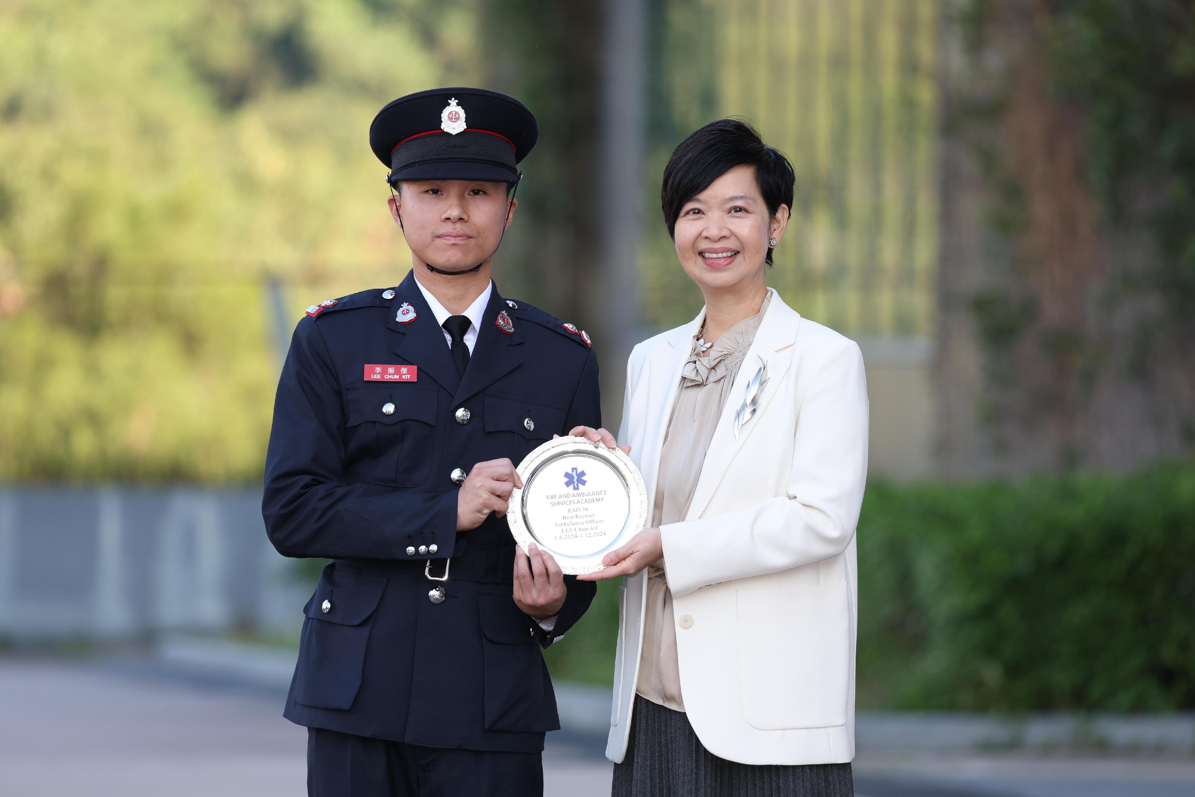 The Secretary for Housing, Ms Winnie Ho, reviewed the Fire Services passing-out parade at the Fire and Ambulance Services Academy today (November 22). Photo shows Ms Ho (right) presenting the Best Recruit Ambulance Officer award to a graduate.