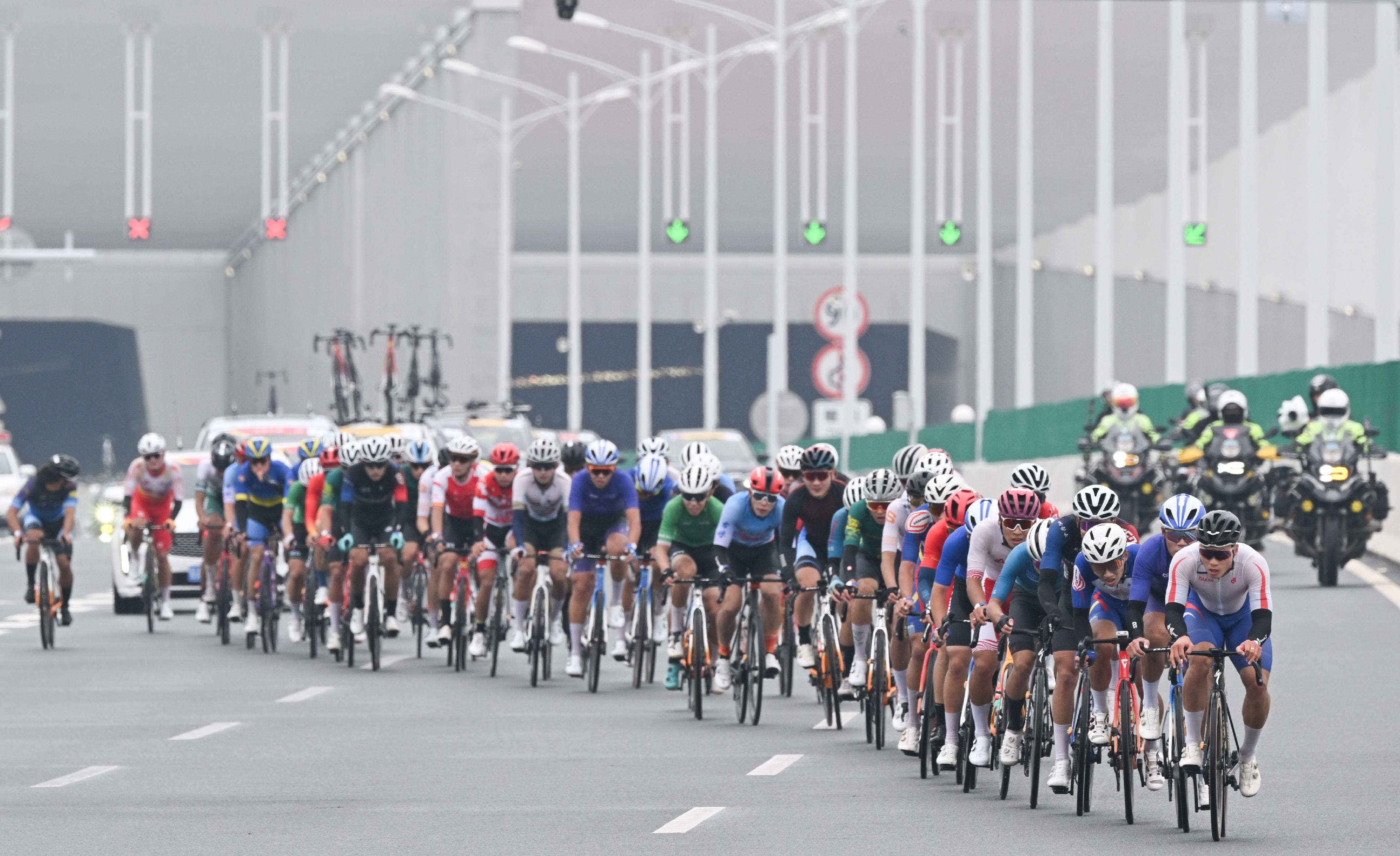 The 2024 Guangdong-Hong Kong-Macao Road Cycling Race and the 15th National Games road cycling test event was held today (November 24) in Zhuhai, Hong Kong and Macao's urban roads and the Hong Kong-Zhuhai-Macao Bridge. Photo shows the road racers entering Hong Kong section via the Hong Kong-Zhuhai-Macao Bridge.