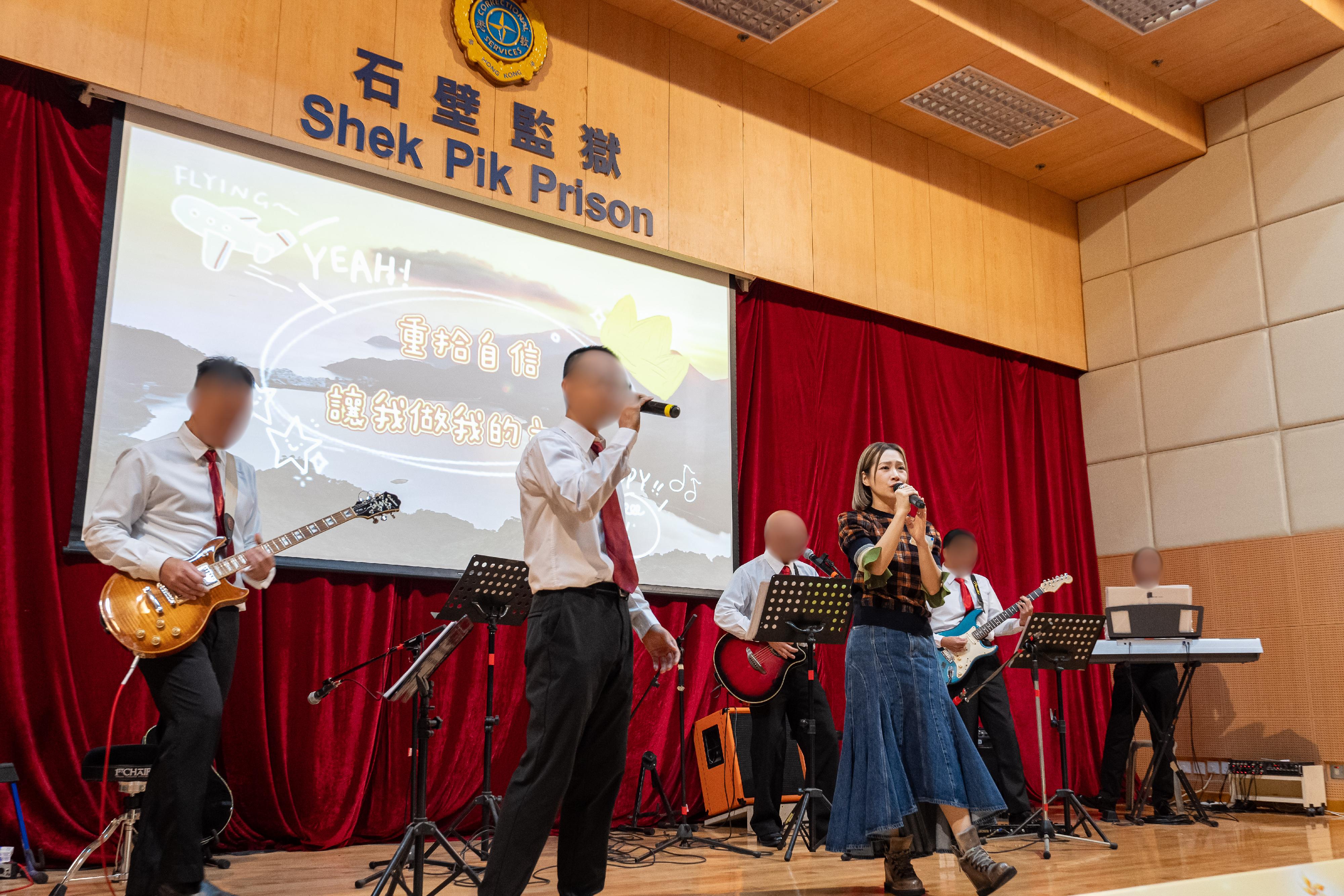 A total of 99 persons in custody at Shek Pik Prison of the Correctional Services Department were presented with certificates at a ceremony today (November 27) in recognition of their study efforts and academic achievements. Photo shows singer Jade Kwan (front row, right), together with a band composed of persons in custody, performing music onstage.