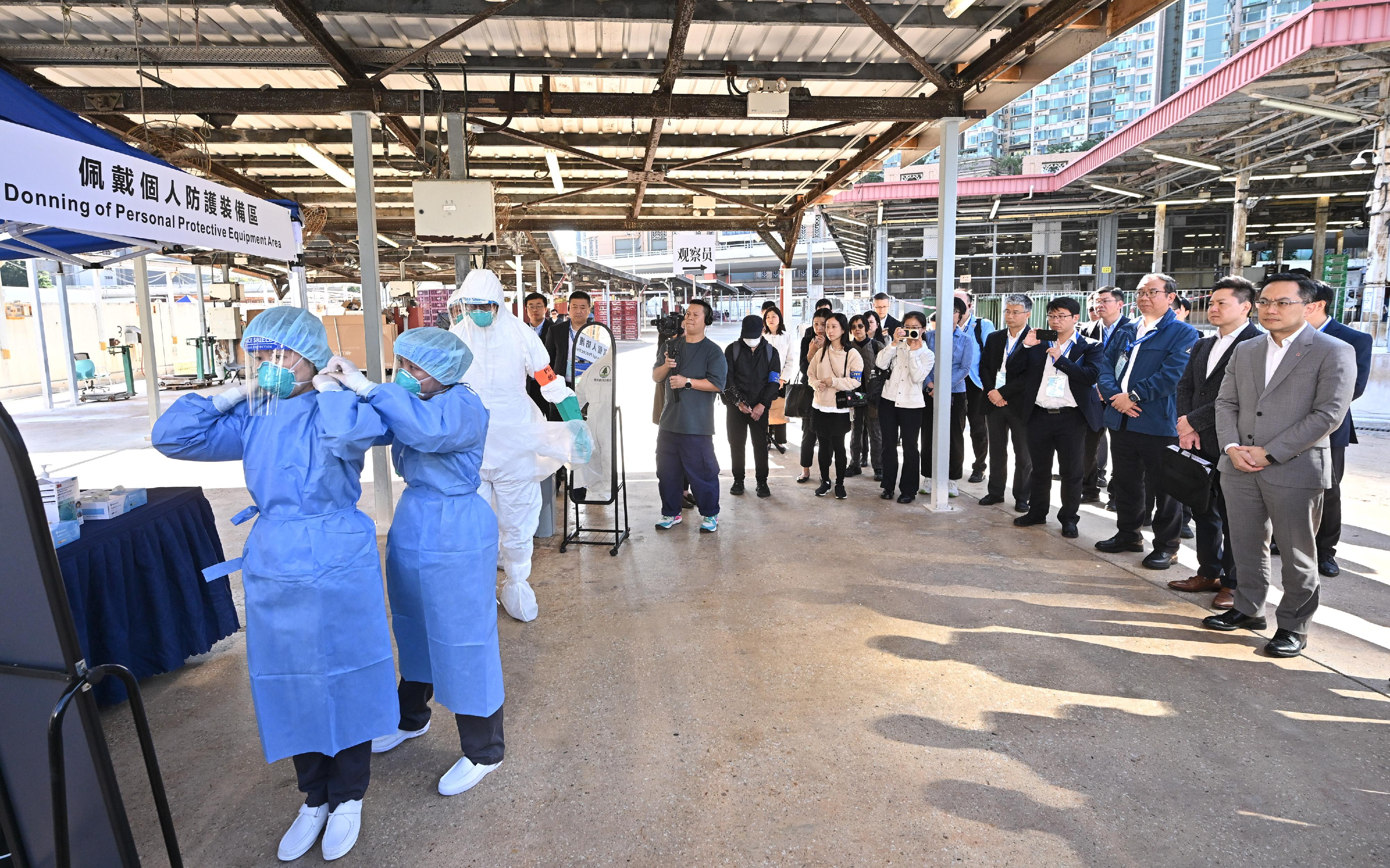 The Centre for Health Protection (CHP) of the Department of Health (DH), in collaboration with relevant government departments, today (November 27) conducted a public health exercise, code-named "Amazonite", to enhance its response capabilities in handling a human case of avian influenza infection. Photo shows the Director of Health, Dr Ronald Lam (first right), the Controller of the CHP of the DH, Dr Edwin Tsui (second right), and experts from the Mainland, Macao and Singapore health authorities observing the donning of personal protective equipment.