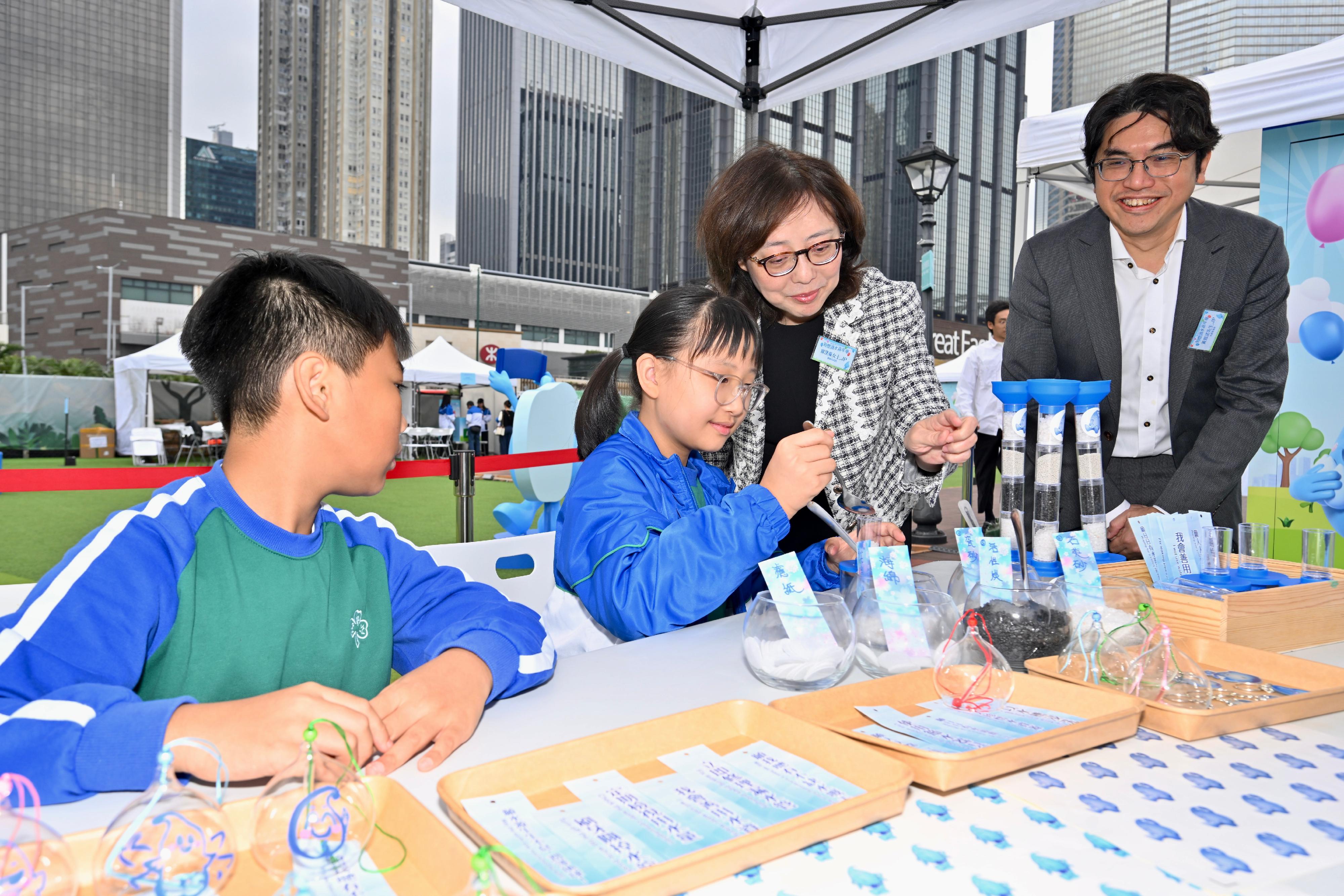 水务署「知悭识水」嘉年华今日（十二月五日）至十二月十五日在湾仔HarbourChill海滨休闲站举行。图示发展局局长甯汉豪（右二）及水务署署长黄恩诺（右一）今日与在场学生参与节水工作坊。