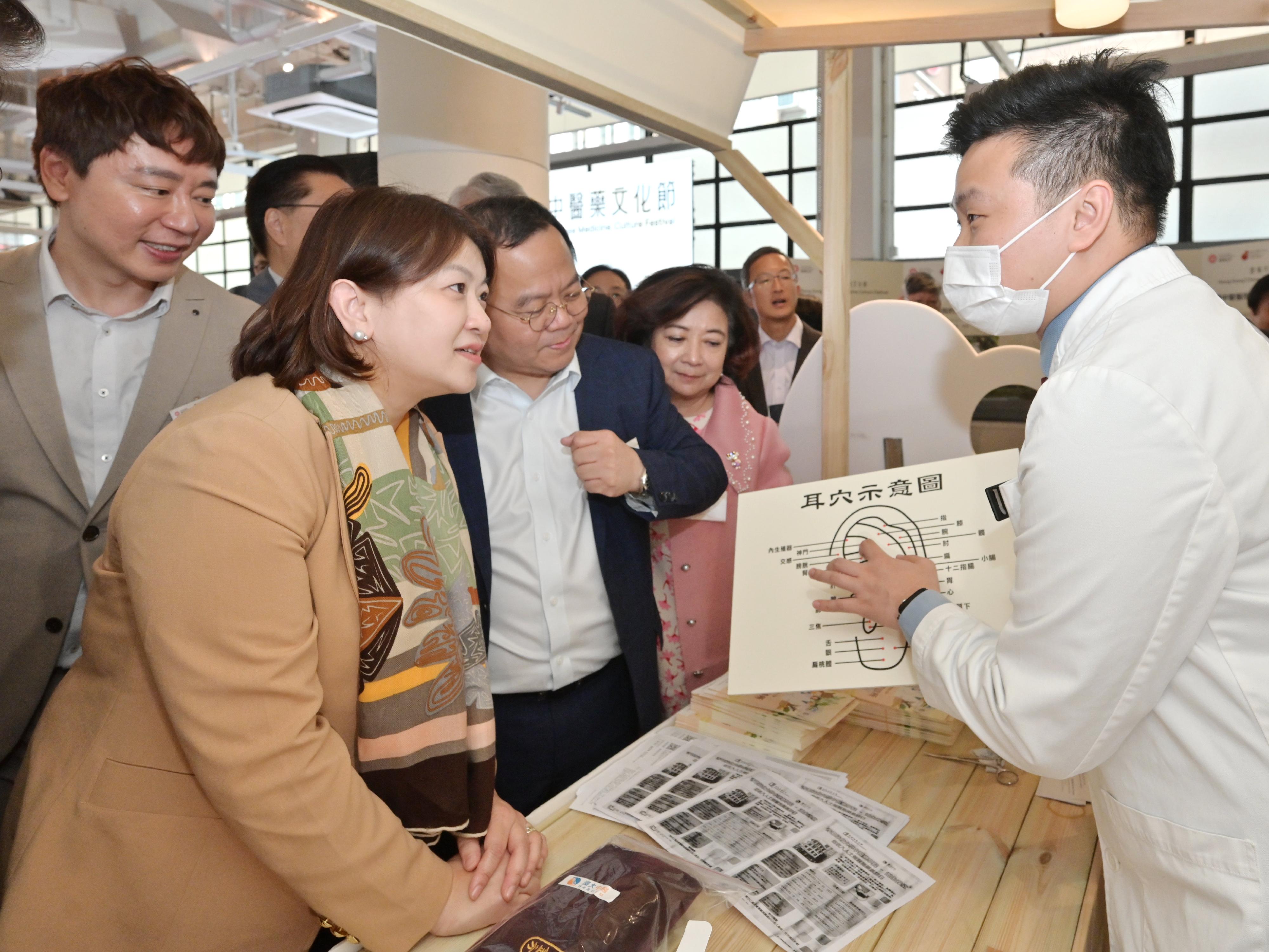 首届「香港中医药文化节」启动活动今日（十二月七日）起一连两日在中环街巿举行。图示署理医务卫生局局长李夏茵医生（左二）参观香港浸会大学中医药学院的摊位。旁为中医药发展专员钟志豪博士（左一）。




