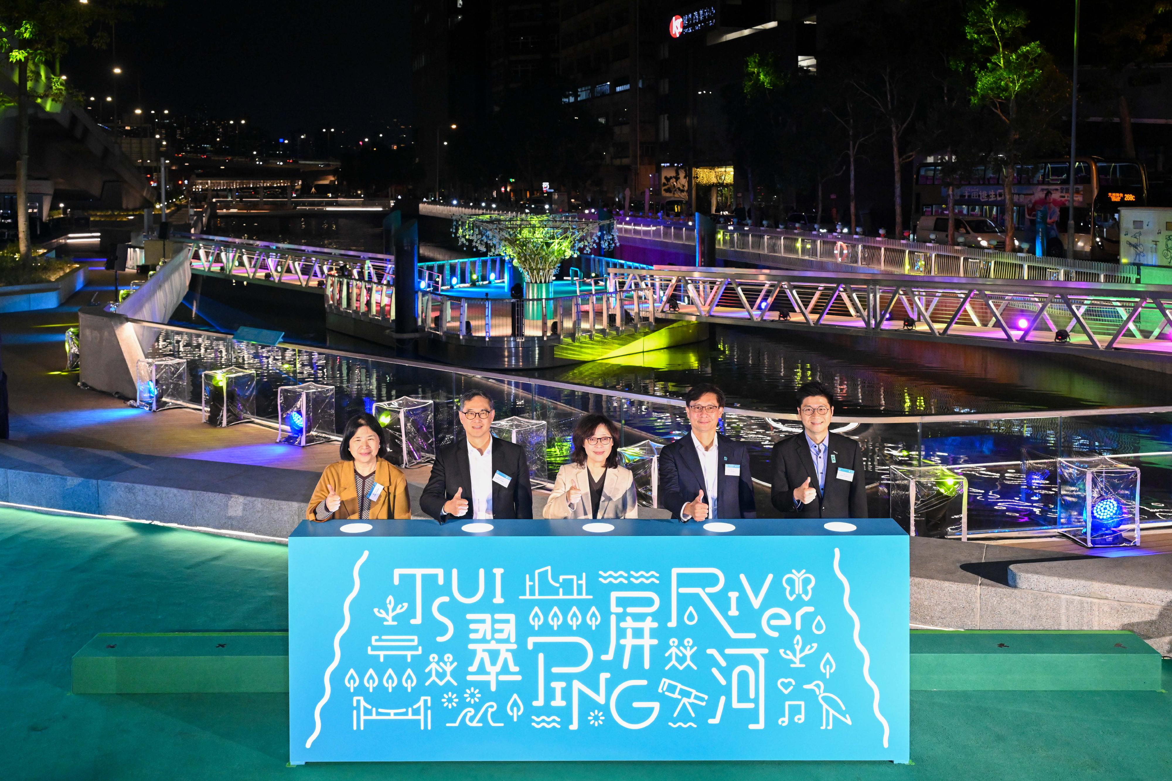 Under the Revitalization of Tsui Ping River project by the Drainage Services Department, the facilities of Tsui Ping River along the King Yip Street section were opened for public use today (December 12). Photo shows the Secretary for Development, Ms Bernadette Linn (centre); the Permanent Secretary for Development (Works), Mr Ricky Lau (second left); the Director of Drainage Services, Mr Ringo Mok (second right); the Head of the Energizing Kowloon East Office, Ms April Kun (first left); and the District Officer (Kwun Tong), Mr Denny Ho (first right), officiating at the lighting ceremony during the opening ceremony.