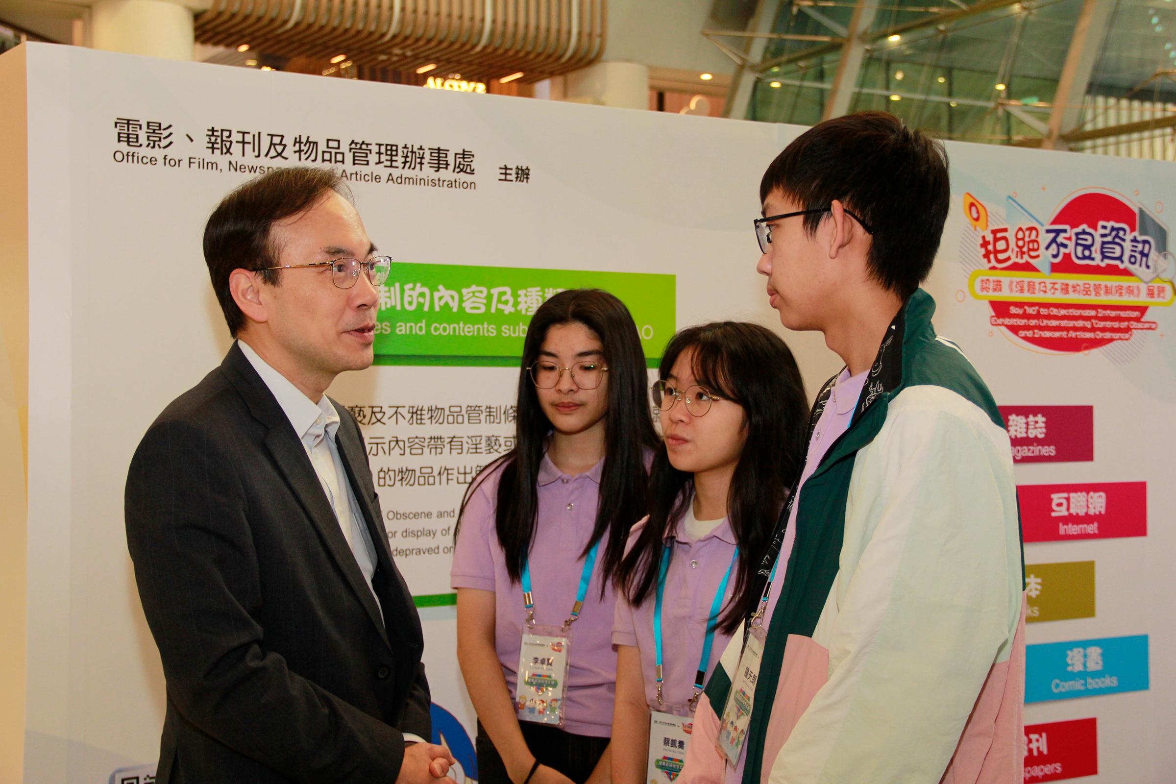 The Office for Film, Newspaper and Article Administration is holding an exhibition themed "Saying NO to Objectionable Information" for three consecutive days starting from today (December 27) to enhance the public's understanding of the Control of Obscene and Indecent Articles Ordinance. Photo shows the Director of Film, Newspaper and Article Administration, Mr Chaucer Leung (first left), interacting with three Healthy Information Student Ambassadors at the exhibition.