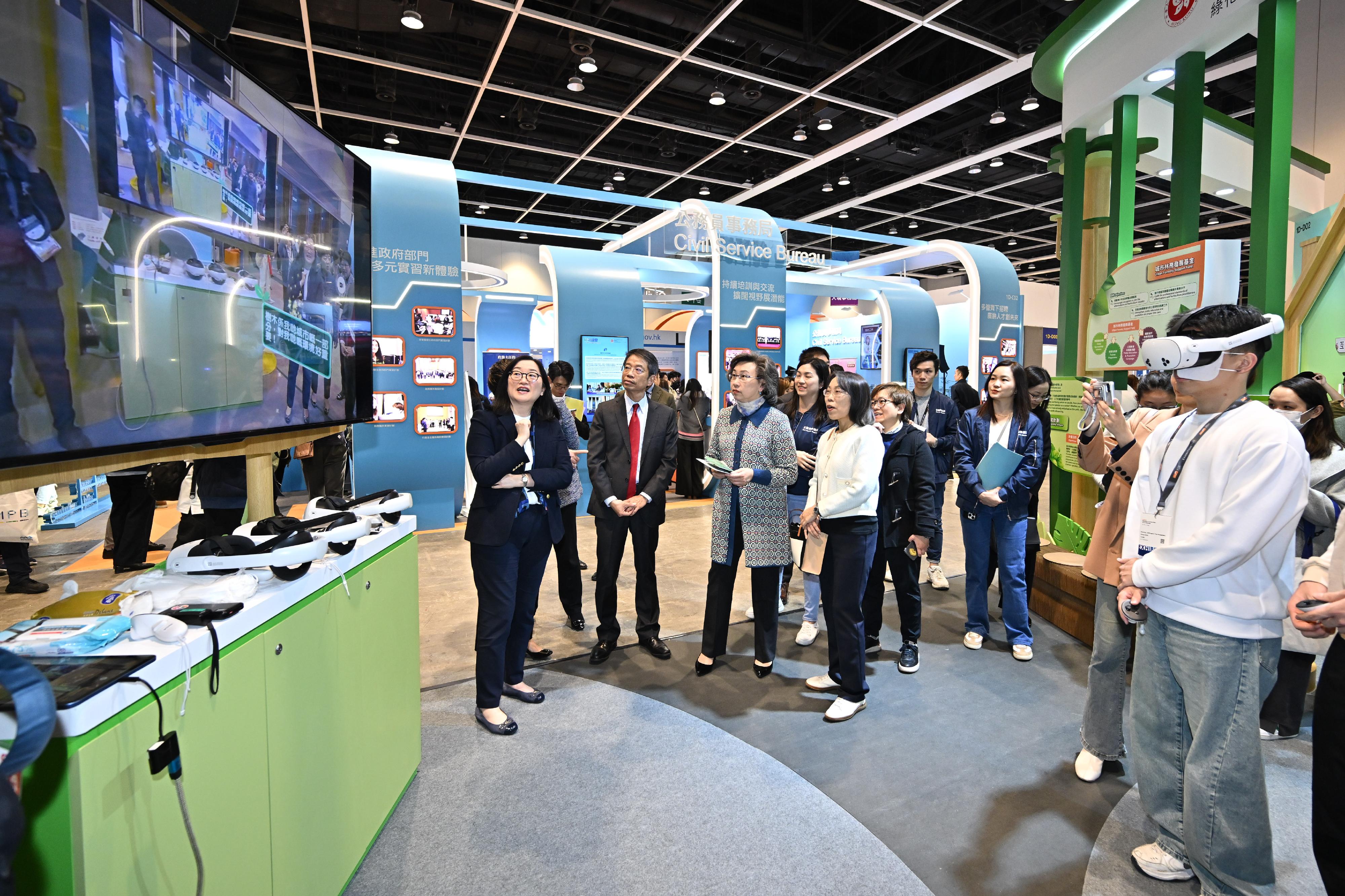 The Civil Service Bureau has curated an exhibition area at the Education & Careers Expo 2025 from today (January 16) for four consecutive days to introduce the work of over 50 government grades and provide the public with information on civil service recruitment to enhance job seekers' understanding of government jobs. Photo shows the Secretary for the Civil Service, Mrs Ingrid Yeung (third left), watching a demonstration of Virtual Reality technology at the Development Bureau's booth. Looking on is the Permanent Secretary for the Civil Service, Mr Clement Leung (second left).