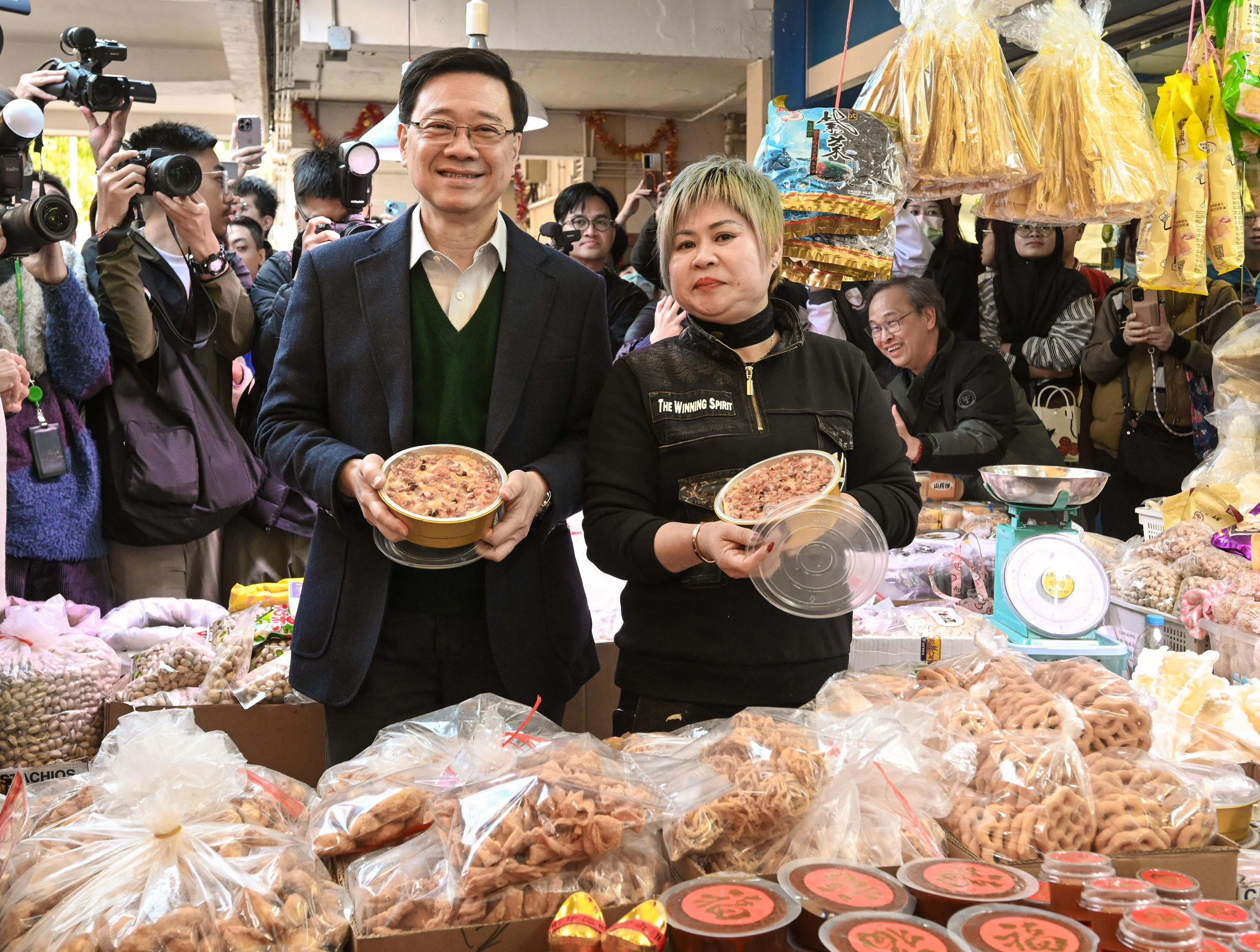 The Chief Executive, Mr John Lee, visited Ho Man Tin today (January 25). Photo shows Mr Lee (left) visiting a shop in Oi Man Market, Kowloon City District, and shopping for Chinese New Year food.