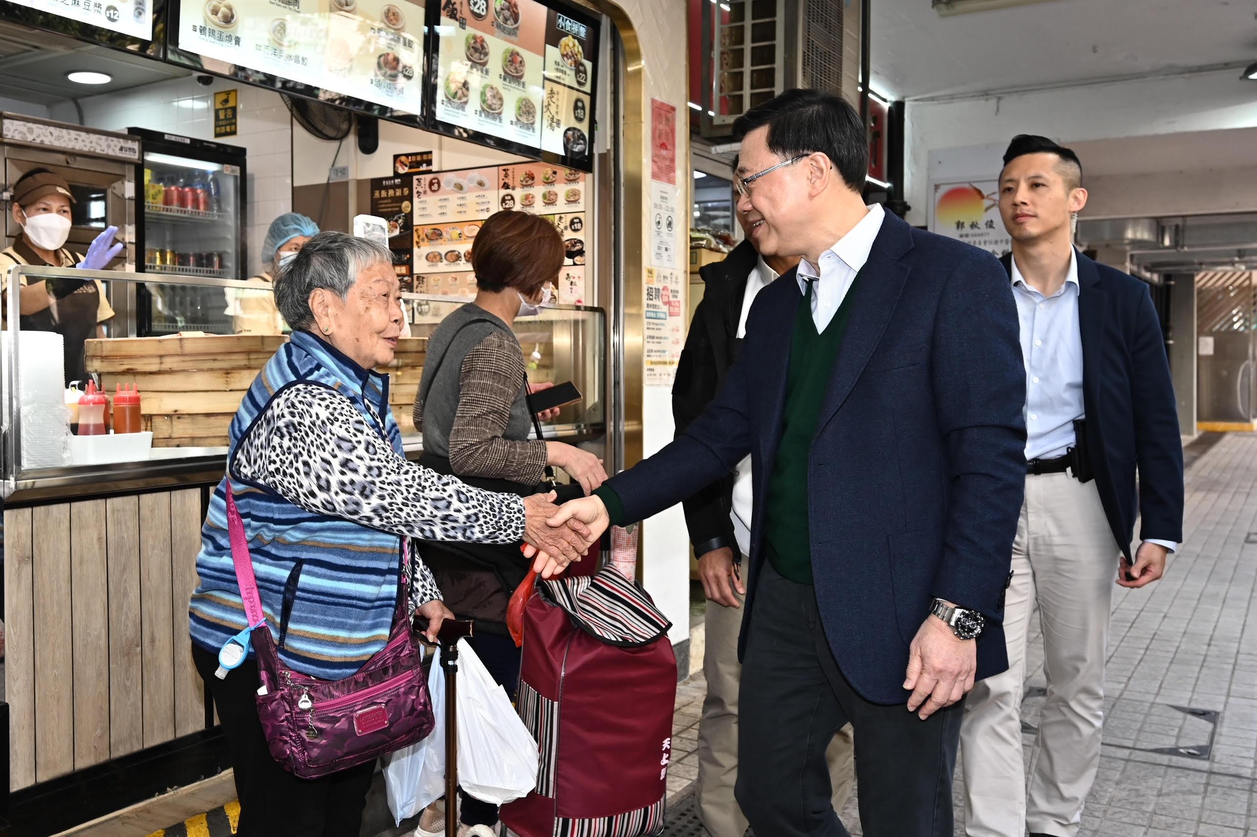 The Chief Executive, Mr John Lee, visited Ho Man Tin today (January 25). Photo shows Mr Lee (second right) visiting Oi Man Estate, Kowloon City District, and interacting with a resident of the district.