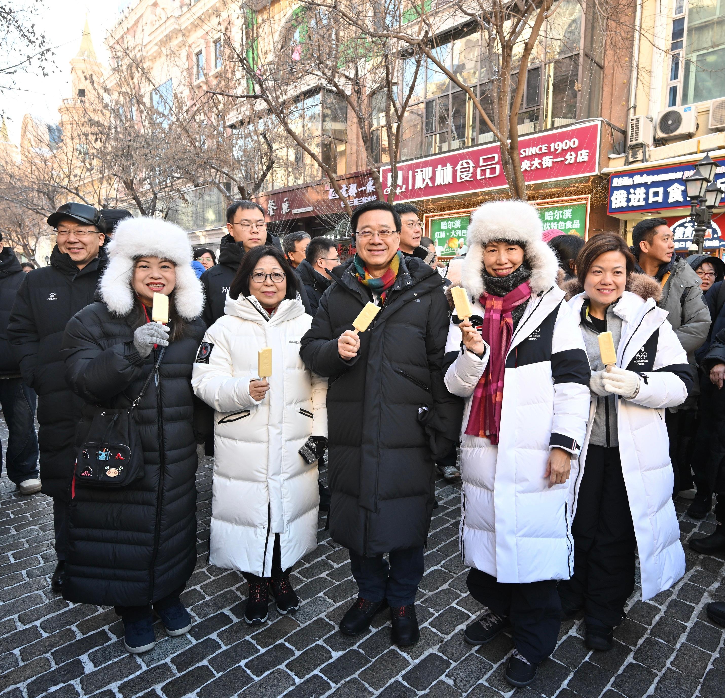 The Chief Executive, Mr John Lee, continued his visit programme in Harbin today (February 8). Photo shows Mr Lee (centre) and his wife Mrs Janet Lee (second left), visiting Zhongyang Street and tasting local snacks.