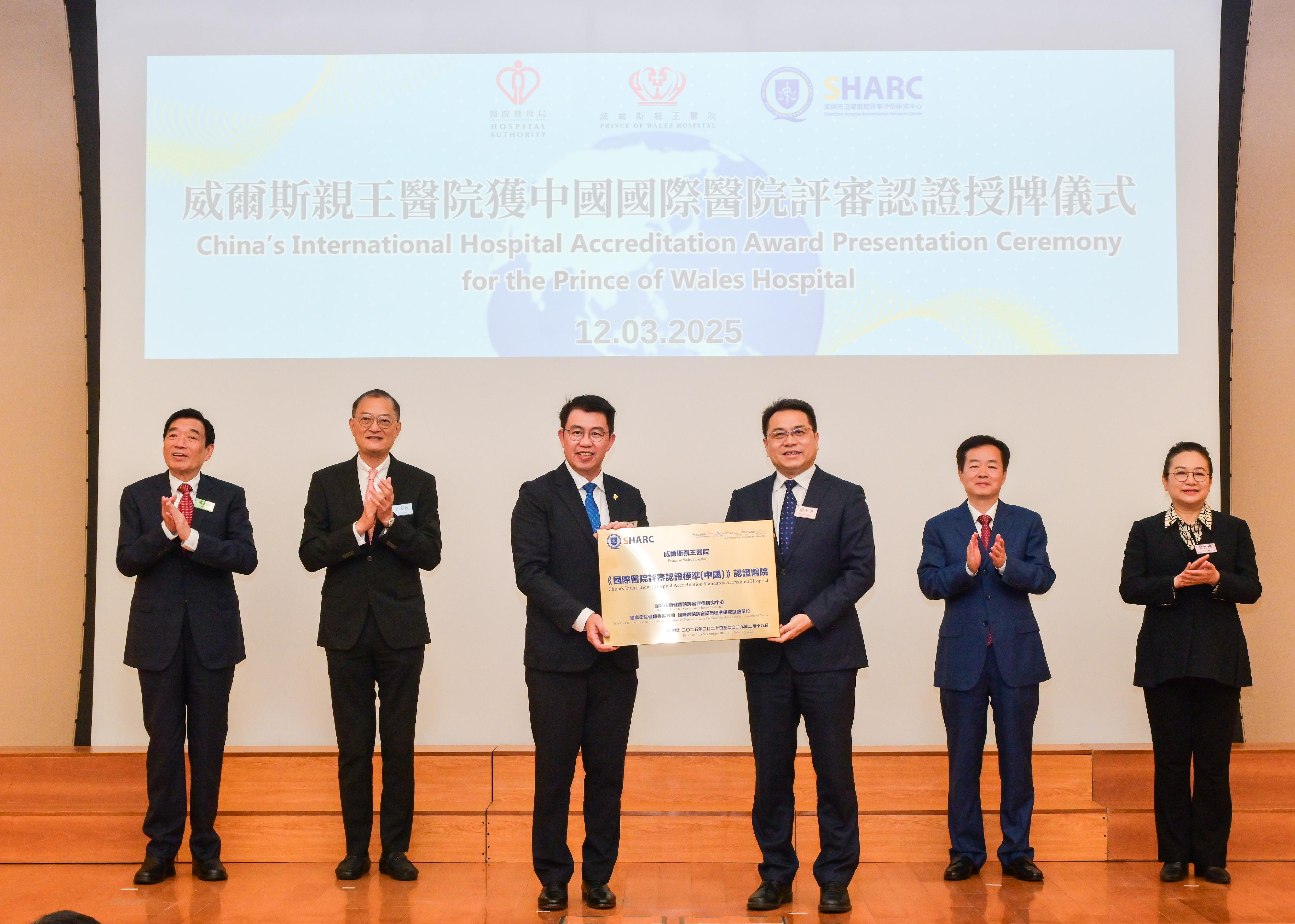 The Secretary for Health, Professor Lo Chung-mau (back row, second left); member of the Standing Committee of the CPC Shenzhen Municipal Committee and the Party Leadership Group of the Shenzhen Municipal People's Government Mr Chen Qing (back row, second right); the Director General of the Public Hygiene and Health Commission of Shenzhen Municipality, Ms Wu Hongyan (back row, first right); and the Chairman of the Hospital Authority, Mr Henry Fan (back row, first left), witnessed the accreditation of the Prince of Wales Hospital (PWH), which becomes the second hospital in the Hong Kong Special Administrative Region accredited under the China's International Hospital Accreditation Standards (2021 Version) today (March 12). Photo shows the President of the Shenzhen Hospital Accreditation Research Center, Mr Xu Xiaoping (front row, right), presenting an accreditation award to the Hospital Chief Executive of PWH, Dr Chung Kin-lai (front row, left). 