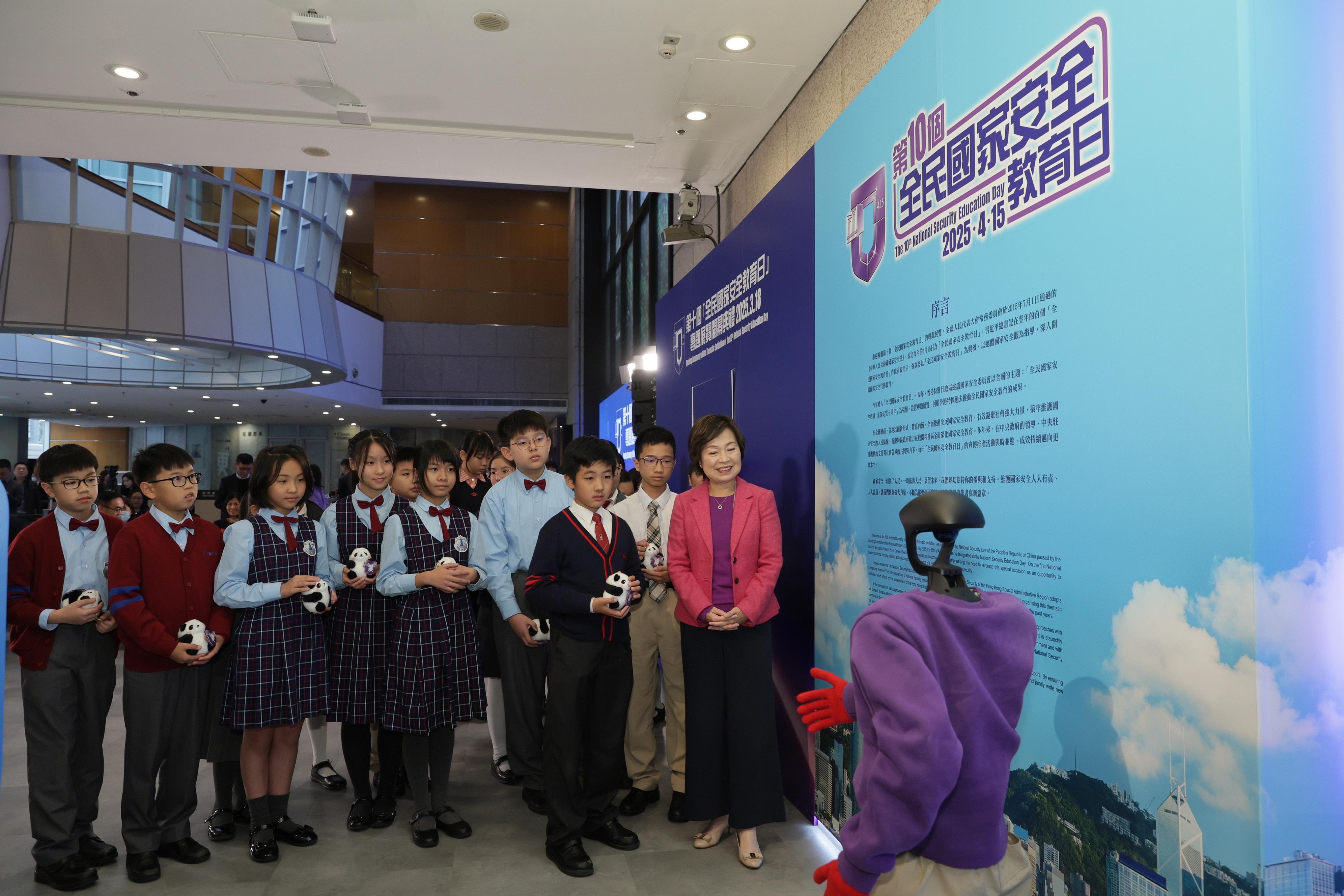 The Secretary for Education, Dr Choi Yuk-lin (first right), and students receive an introduction by the robotic docent on the display panels at the 10th National Security Education Day thematic exhibition today (March 18).