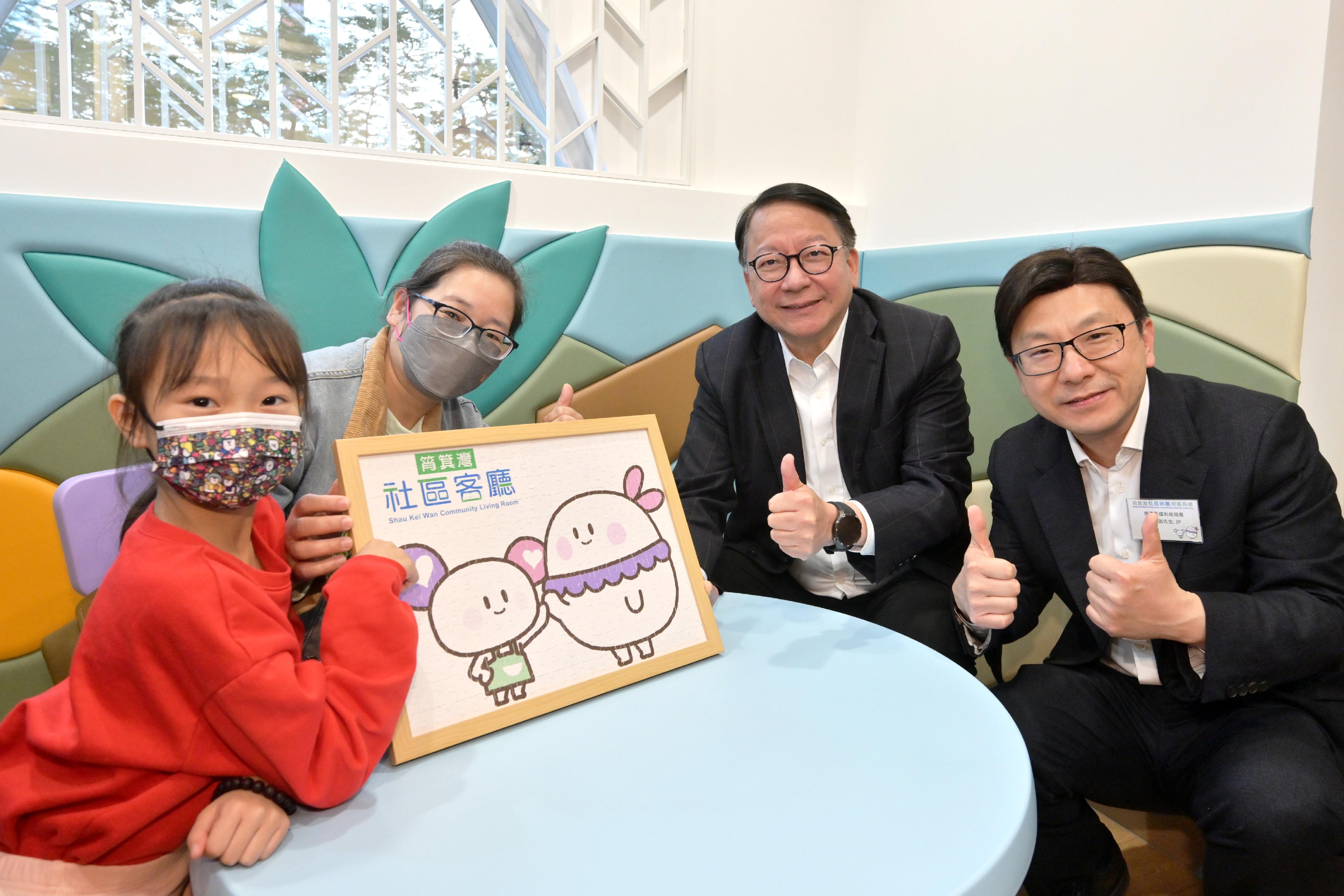 政務司司長陳國基今日（三月十九日）主持筲箕灣社區客廳開幕典禮，慶祝港島區首個社區客廳投入服務。勞工及福利局局長孫玉菡亦一同主禮。圖示陳國基（右二）和孫玉菡（右一）在遊戲室與受惠人士合照，並了解他們對社區客廳設施的意見。