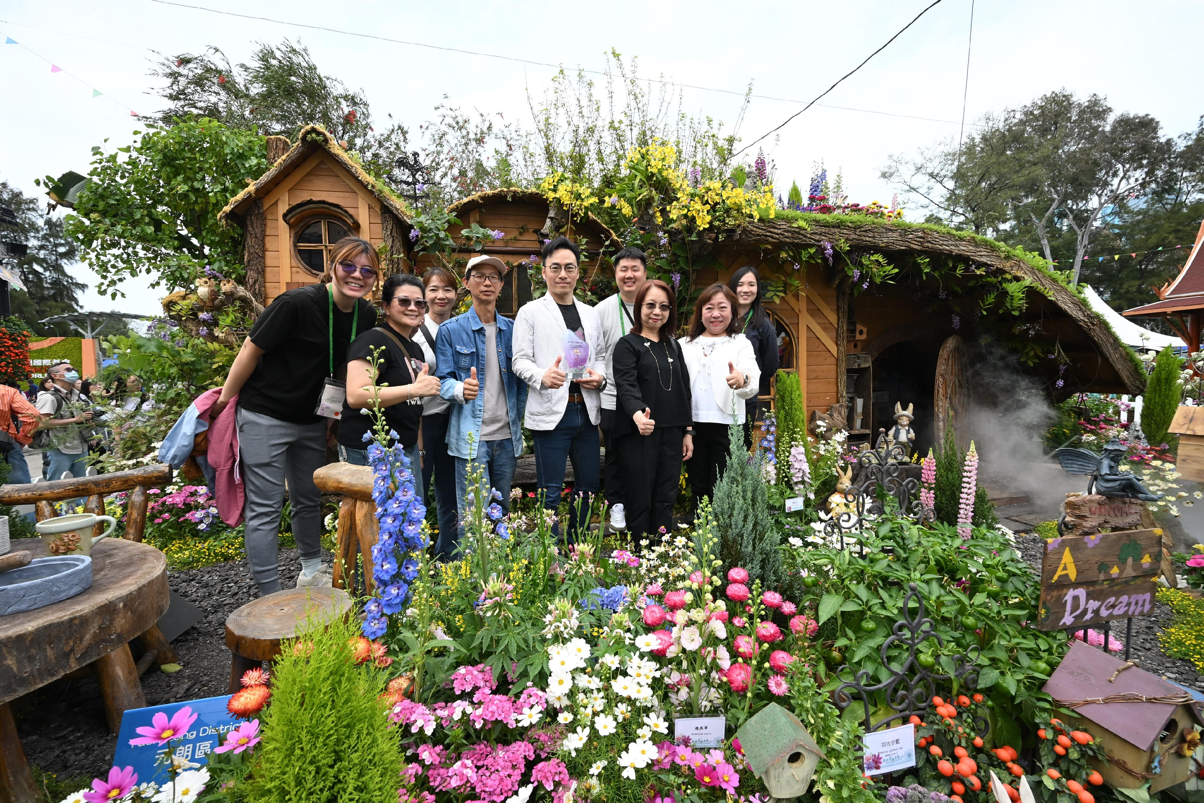 The Hong Kong Flower Show 2025, currently running at Victoria Park, is displaying the winning entries of the Leisure and Cultural Services Department (LCSD)'s Western and Oriental Style Garden Plot Competitions. Photo shows staff of the LCSD's Yuen Long District Leisure Services Office in front of their winning Western-style garden plot "The Happy Cottage".

