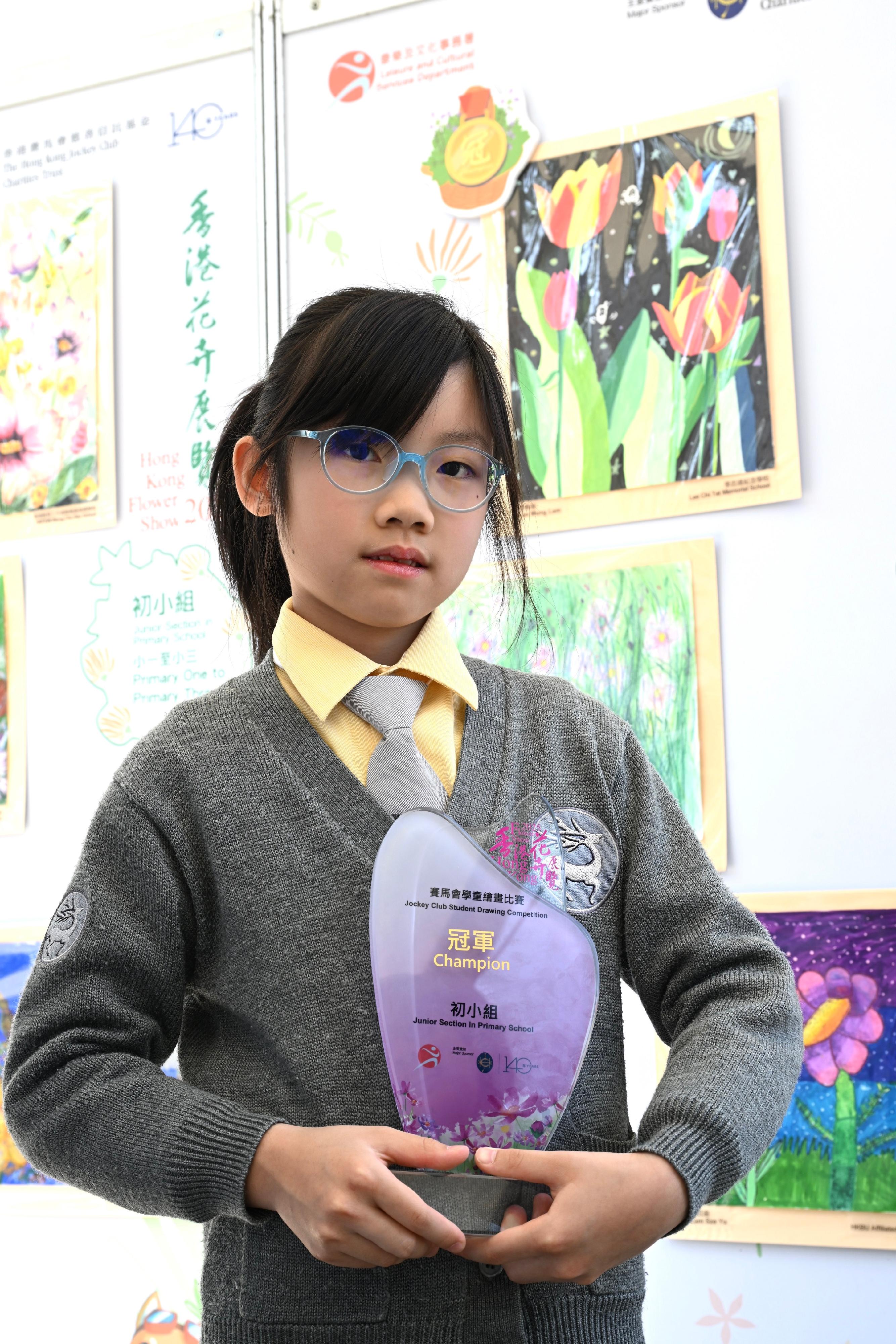 The Hong Kong Flower Show at Victoria Park will close at 9pm tomorrow (March 23). During the show period, various recreational fringe activities have been held, among which the Jockey Club Student Drawing Competition held its prize presentation ceremony today (March 22) and winning entries are now on display at the showground. The competition was conducted in five categories. Photo shows the champion of the Junior Section in Primary School, Lee Mung-lam, and her work.
