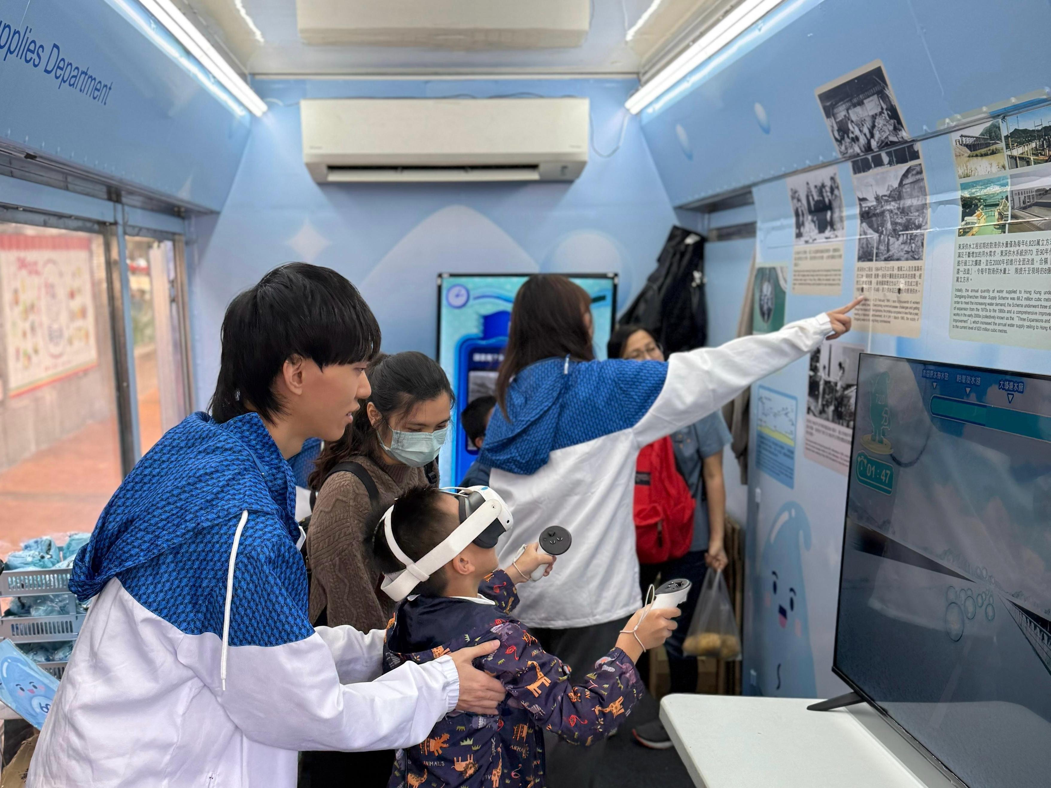 To raise public awareness of the history and the current situation of Dongjiang water supply to Hong Kong, the Water Supplies Department arranged for a mobile exhibition vehicle to tour different districts and schools starting from today (March 22) until April 13. Photo shows the public visiting the mobile exhibition vehicle and experiencing  a virtual reality game.