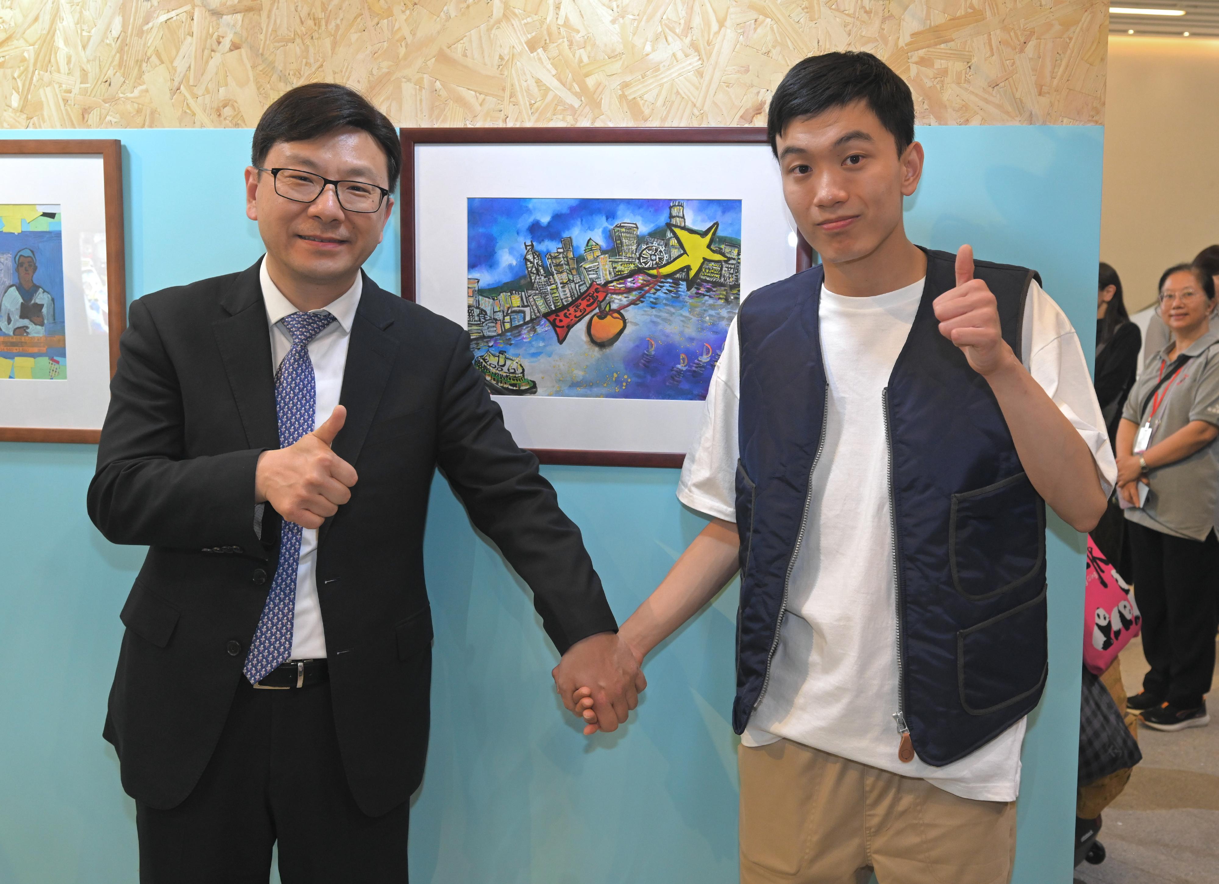 The Secretary for Labour and Welfare, Mr Chris Sun, officiated at the opening ceremony of the Diversity and Inclusion Arts Festival and Diverse Abilities · Inclusive Workplace Recognition Scheme today (March 25). Photo shows Mr Sun (left) in a picture with an artist with a disability and his work during Mr Sun's visit to the exhibition.