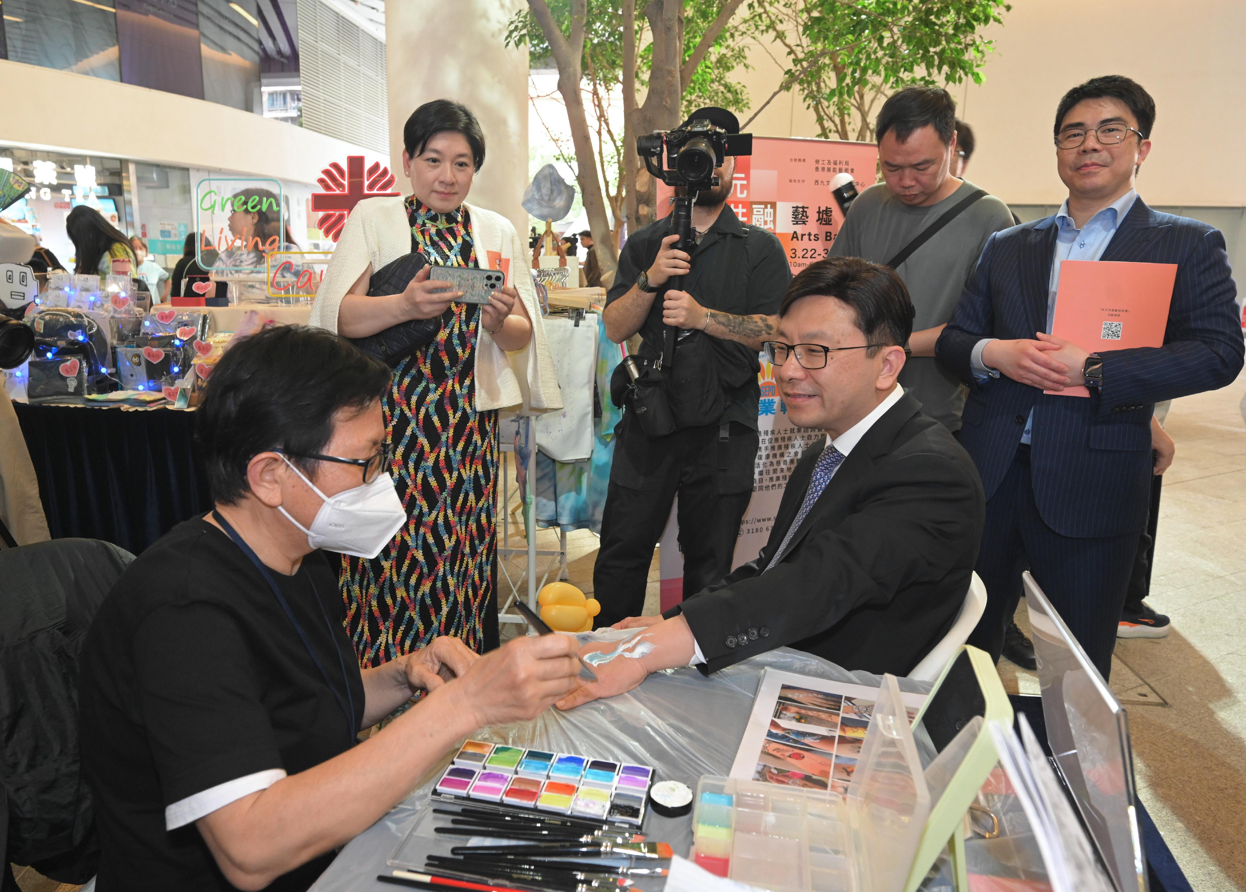 The Secretary for Labour and Welfare, Mr Chris Sun, officiated at the opening ceremony of the Diversity and Inclusion Arts Festival and Diverse Abilities · Inclusive Workplace Recognition Scheme today (March 25). Photo shows Mr Sun (front row, right) visiting the arts bazaar and chatting with a person with a disability.