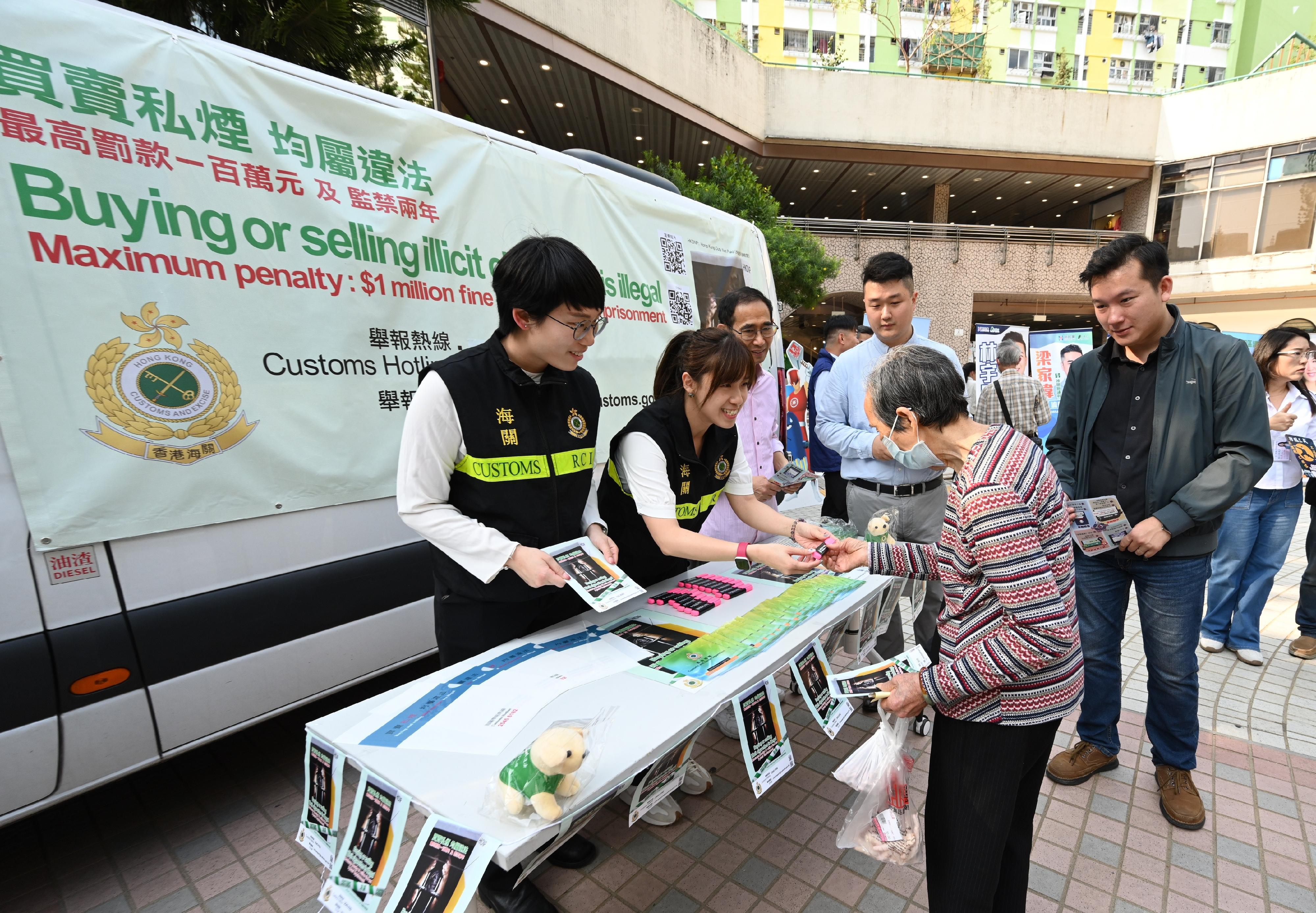 Hong Kong Customs conducted a joint anti-illicit cigarette publicity campaign with members of the Sha Tin District Council and government departments today (March 26). Photo shows Customs officers explaining anti-illicit cigarette messages to a resident.