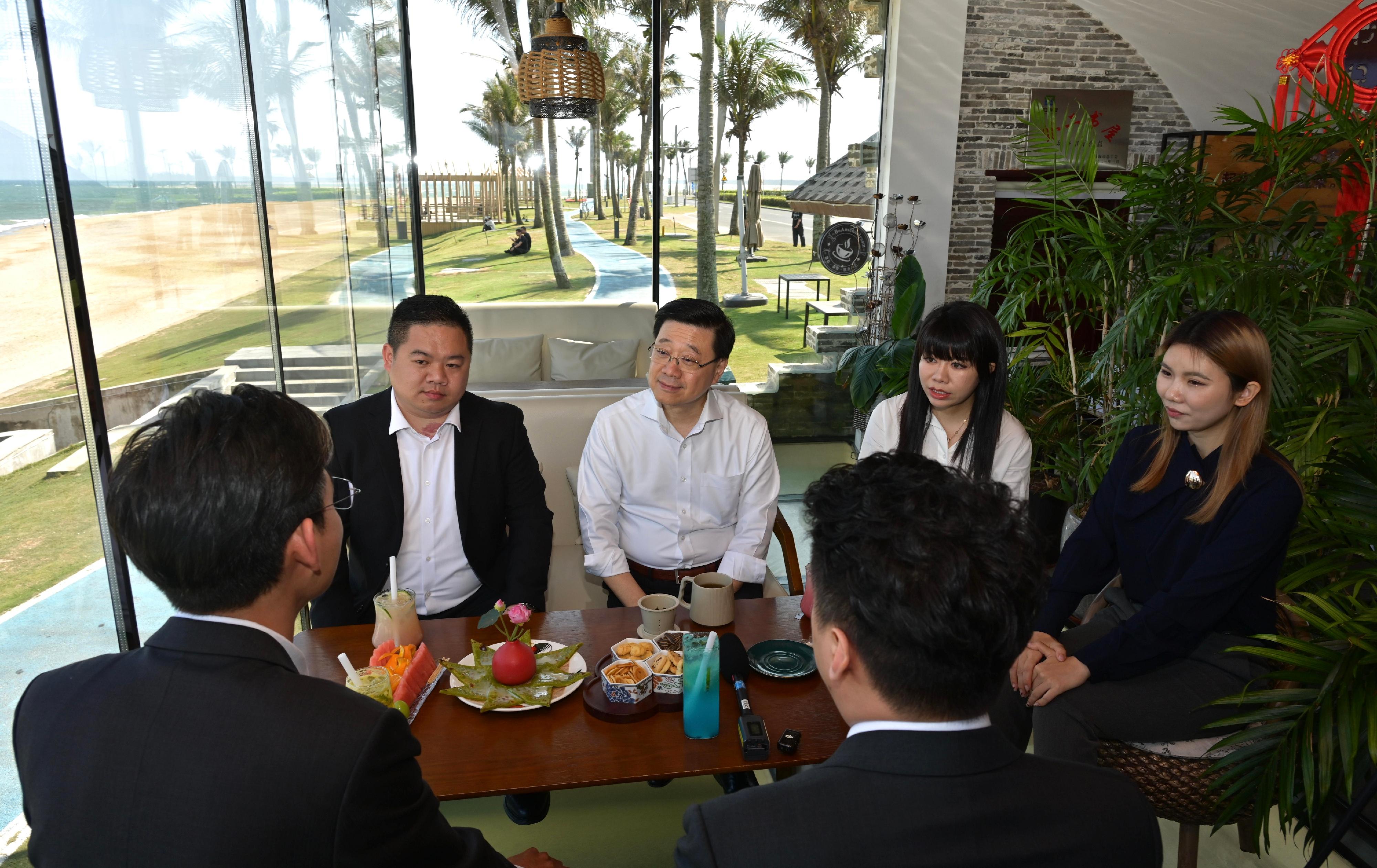The Chief Executive, Mr John Lee, continued his visit to Hainan today (March 26). Photo shows Mr Lee (back row, second left) exchanging views with young people from Hong Kong who are starting businesses and working in Hainan.