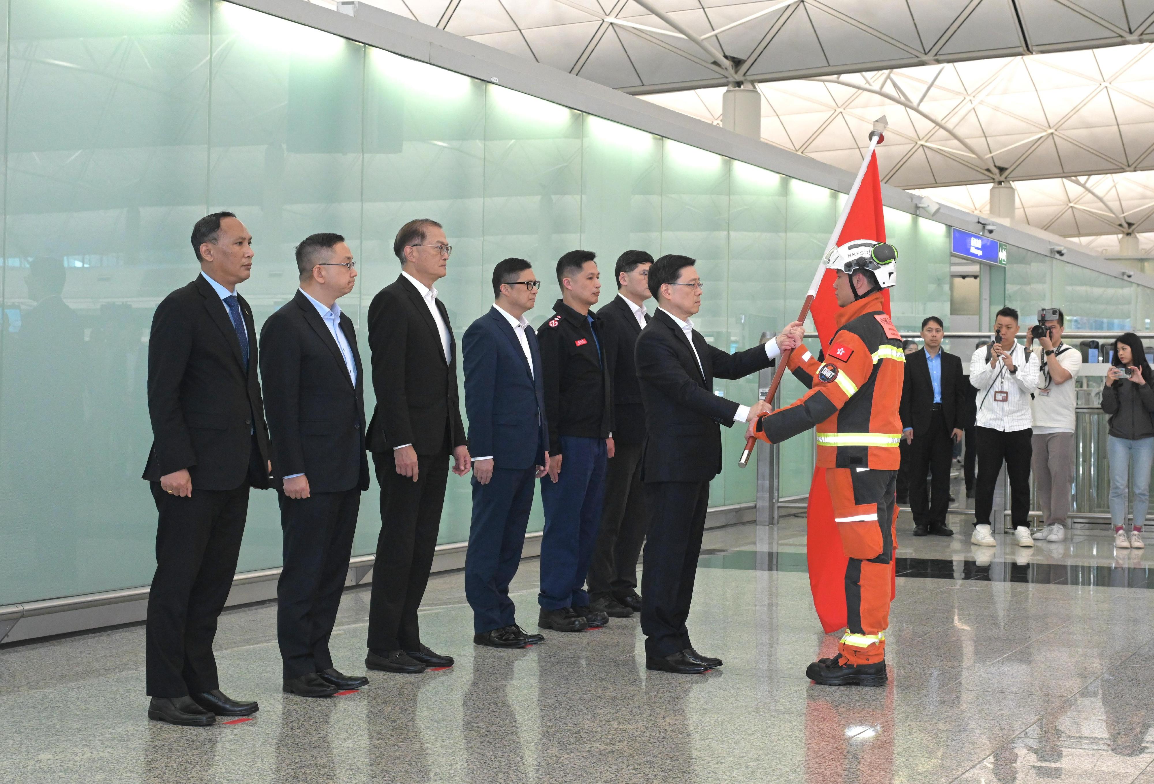 The Hong Kong Special Administrative Region (HKSAR) Government today (March 29) sent a search and rescue team comprising officers from the Security Bureau, the Fire Services Department, the Immigration Department and the Hospital Authority to Myanmar to assist in the search and rescue work at the earthquake-stricken areas. Photo shows the Chief Executive, Mr John Lee (second right), presenting the flag to the representative of the HKSAR search and rescue team.