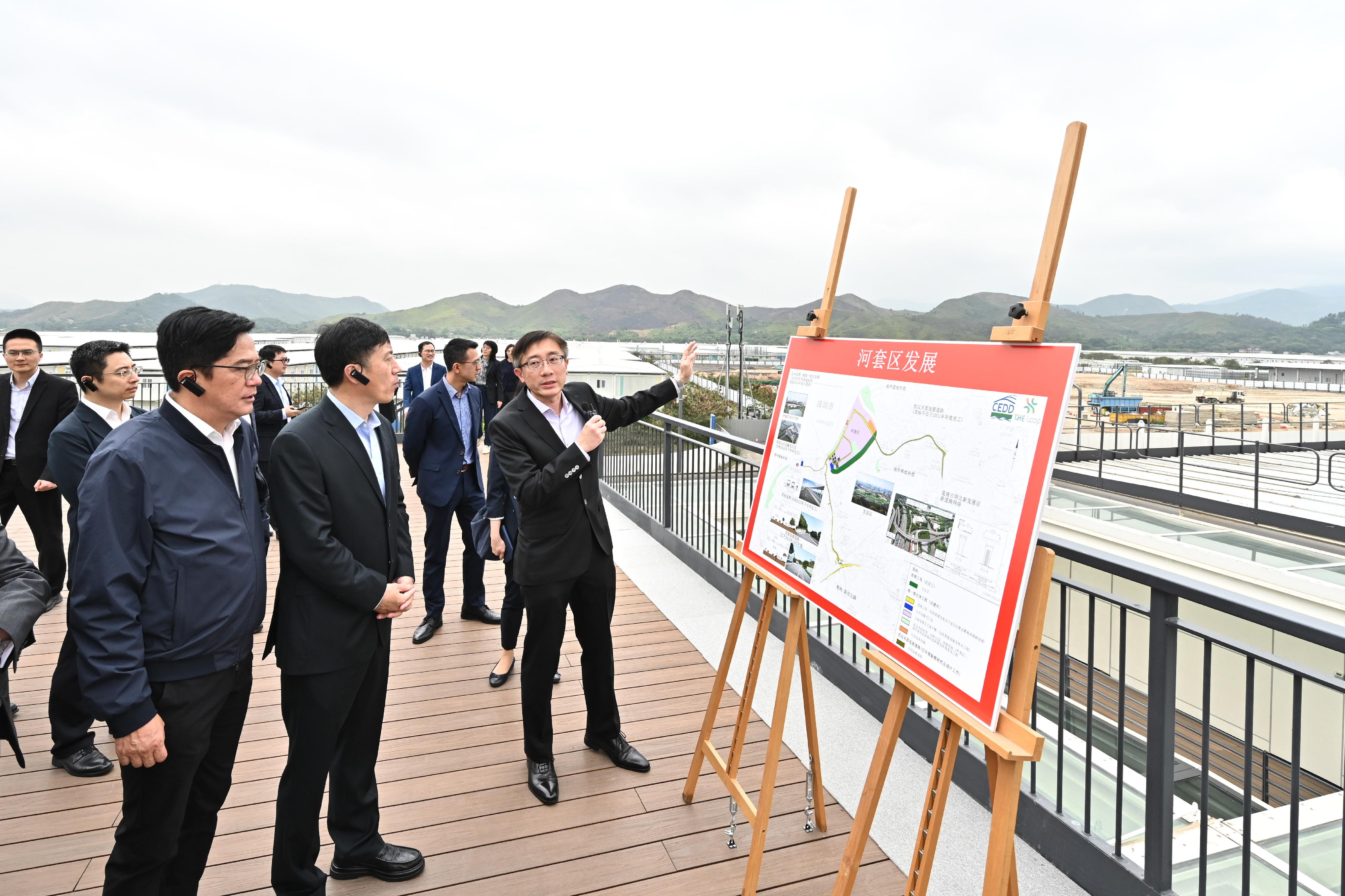 財政司副司長黃偉綸今日（四月十一日）率領香港特別行政區政府代表團，與深圳市常務副市長陶永欣率領的深圳市政府代表團，在香港舉行「對接北部都會區發展策略專班」第六次會議。圖示黃偉綸（左一）、陶永欣（中）與特區政府代表團及深圳市政府代表團，在會議前到訪河套深港科技創新合作區香港園區，聽取土木工程拓展署西拓展處處長陳家豪（右一）介紹園區在規劃、設計及建設方面的情況。