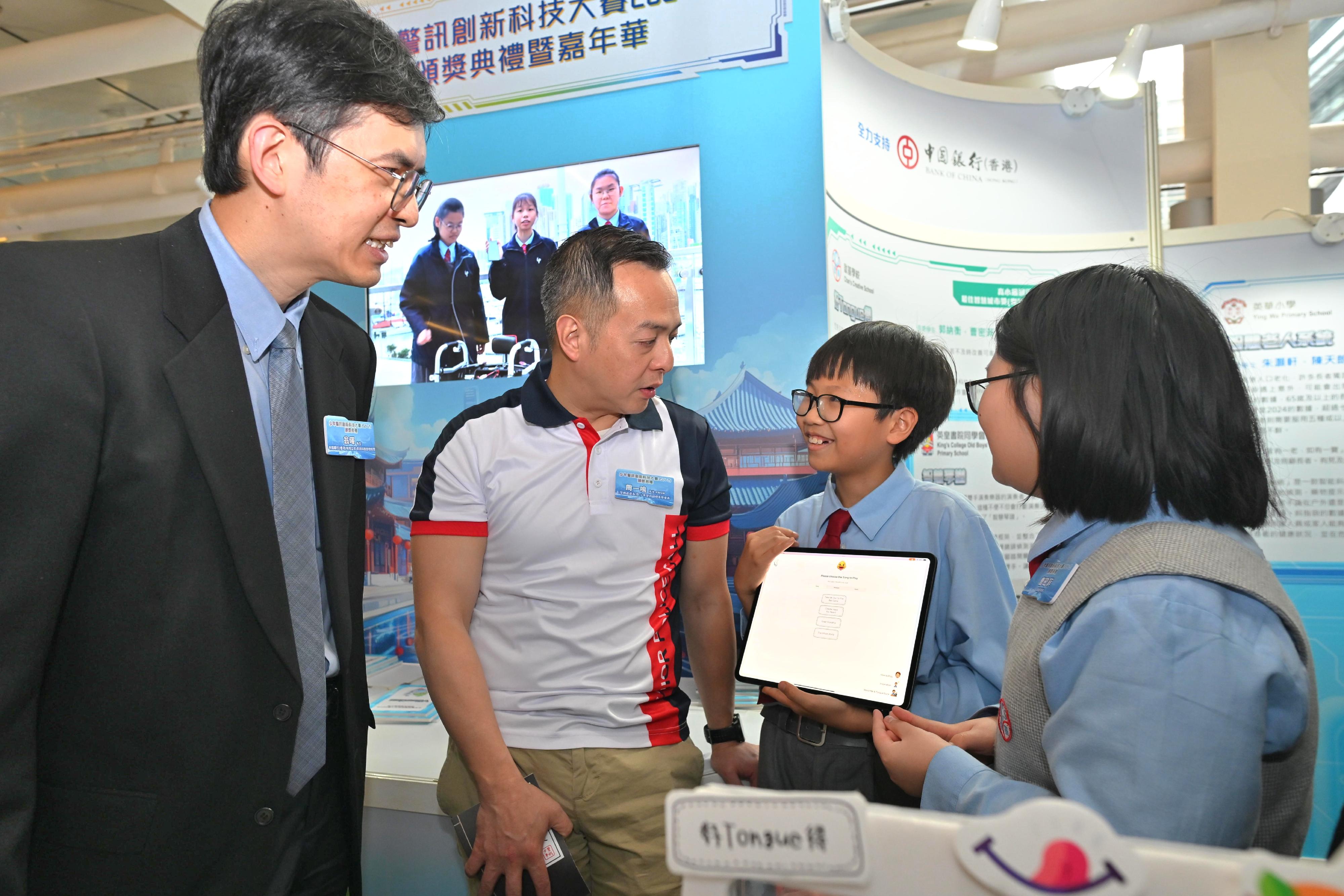 「少年警訊創新科技大賽2024-25」今日（四月十二日）在香港科學園舉行頒獎典禮。圖示高小組冠軍隊伍向警務處處長周一鳴（左二）及中國銀行（香港）資訊科技部總經理翁暉（左一）介紹得奬作品。