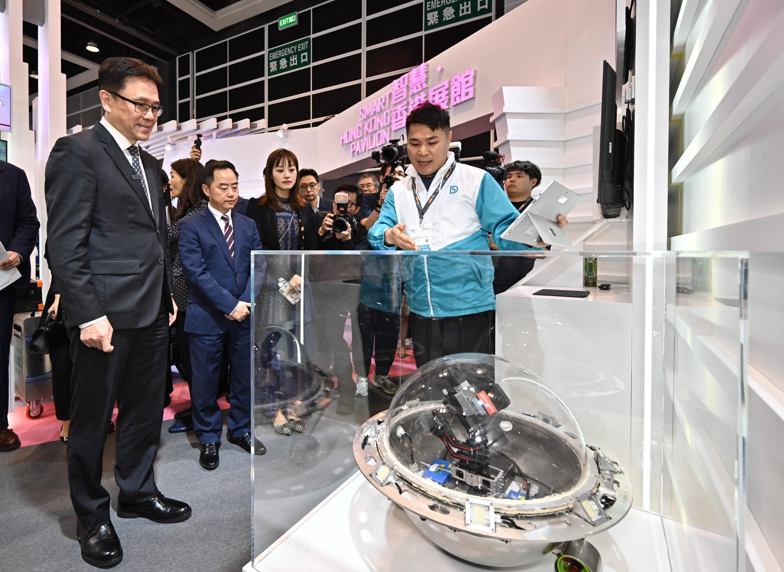 The Secretary for Innovation, Technology and Industry, Professor Sun Dong (first left), visited the Smart Hong Kong Pavilion at InnoEX today (April 13) and was briefed on the Drainage Services Department's Tumbler Inspection Ball Robot with Embodied Intelligence. Looking on are the Under Secretary for Innovation, Technology and Industry, Ms Lillian Cheong (third left); and the Commissioner for Digital Policy, Mr Tony Wong (second left).