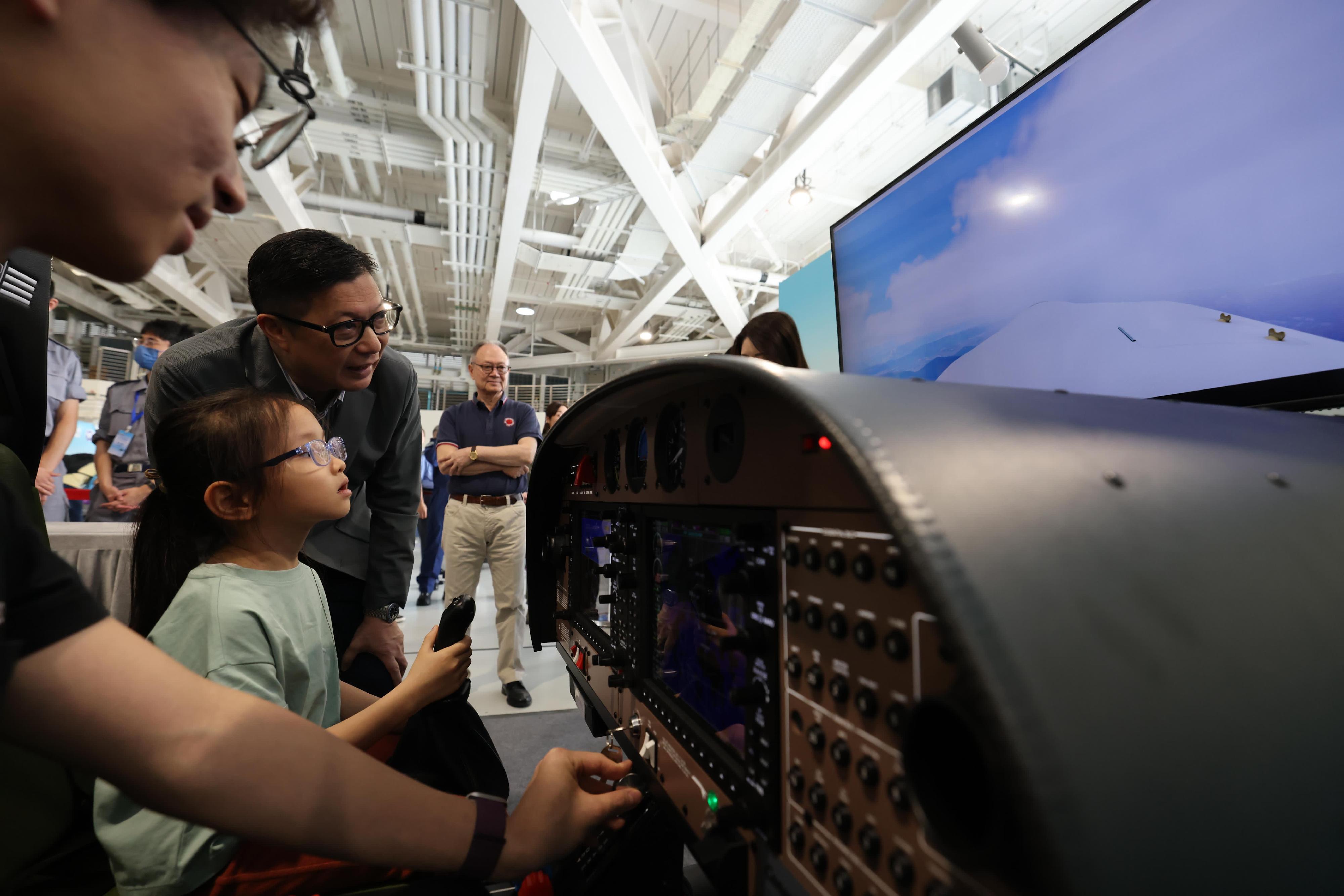 To promote the National Security Education Day, the Government Flying Service (GFS) held an open day today (April 13) at the GFS Kai Tak Division. Photo shows the Secretary for Security, Mr Tang Ping-keung (second right), enjoying flight simulator with a member of the public.