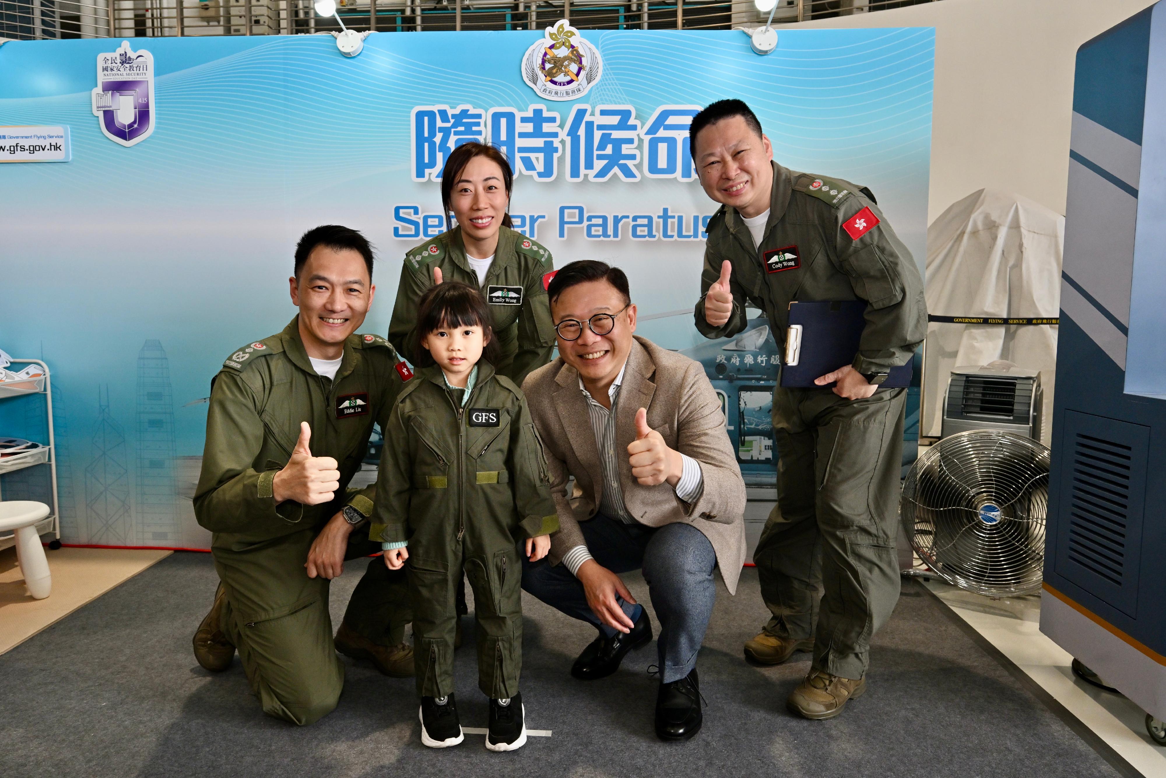 To promote the National Security Education Day, the Government Flying Service (GFS) held an open day today (April 13) at the GFS Kai Tak Division. Photo shows the Deputy Secretary for Justice, Dr Cheung Kwok-kwan (right, front row), and the Controller of GFS, Captain Eddie Liu (left, front row), taking a photo with a member of the public visiting the exhibition booth.
