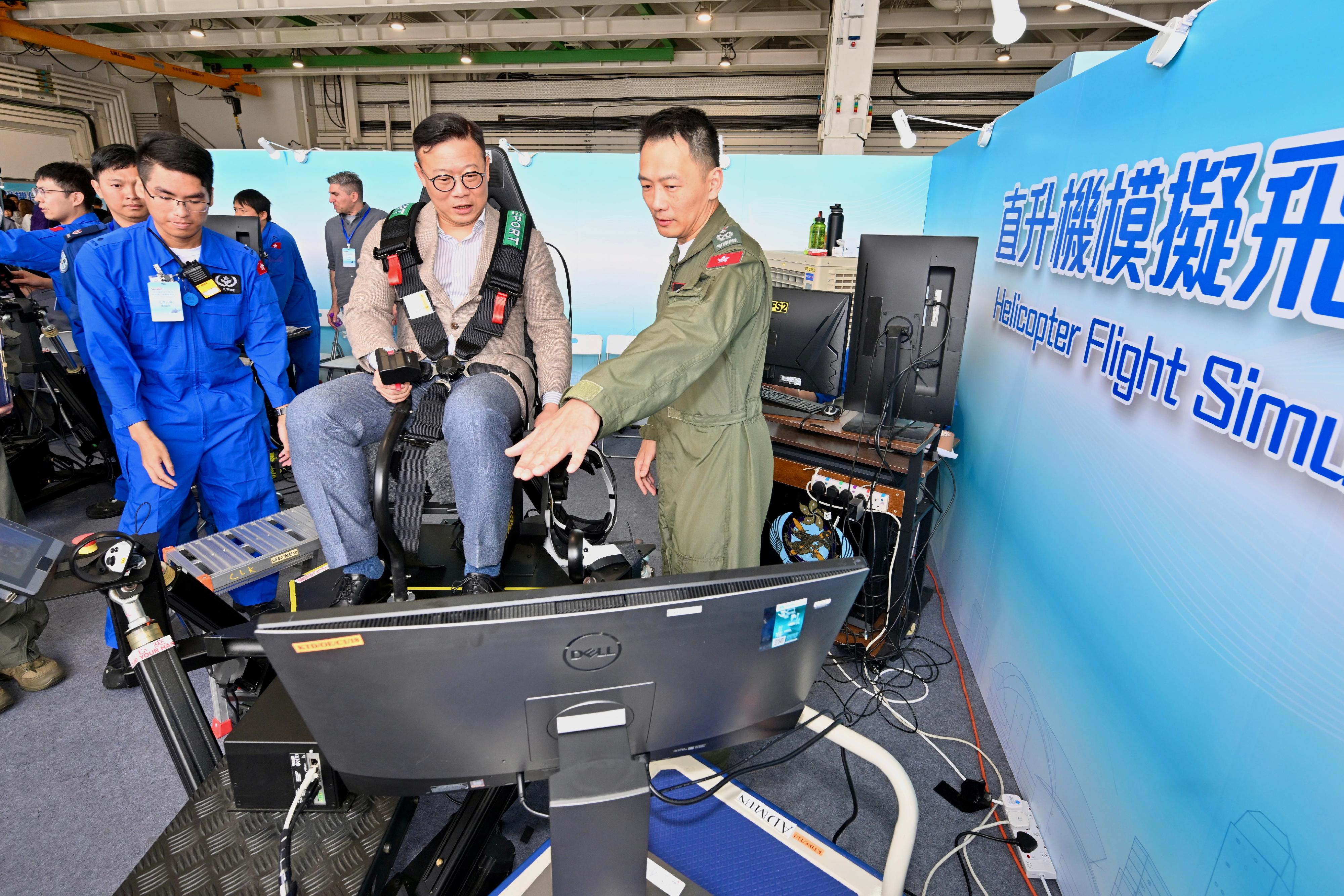 To promote the National Security Education Day, the Government Flying Service (GFS) held an open day today (April 13) at the GFS Kai Tak Division. Photo shows the Deputy Secretary for Justice, Dr Cheung Kwok-kwan (centre), accompanied by the Controller of GFS, Captain Eddie Liu (right), having helicopter flight simulation experience.
