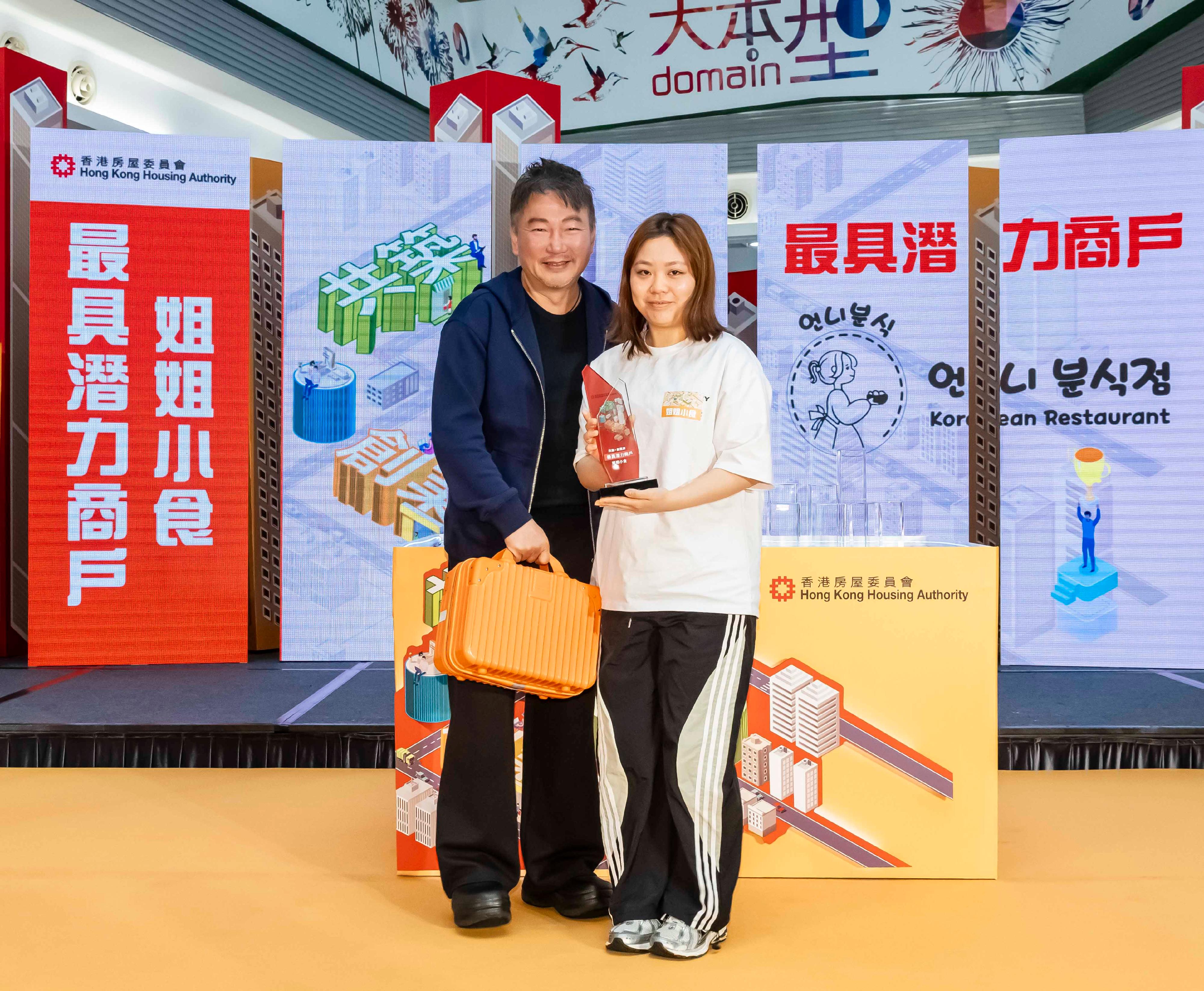 The Hong Kong Housing Authority announced the Well Being·Start-Up 2.0 Programme today (April 17), joining hands with private shopping centres and commercial partners to continue its support for youth entrepreneurship and inject vitality and innovation into the community. Photo shows the Well Being·Start-Up Programme's mentor and Founder of Taste of Asia Group, Mr Ping Orr (left), presenting the Most Promising Business award to a representative of the winner, Korean Sister's Snack.