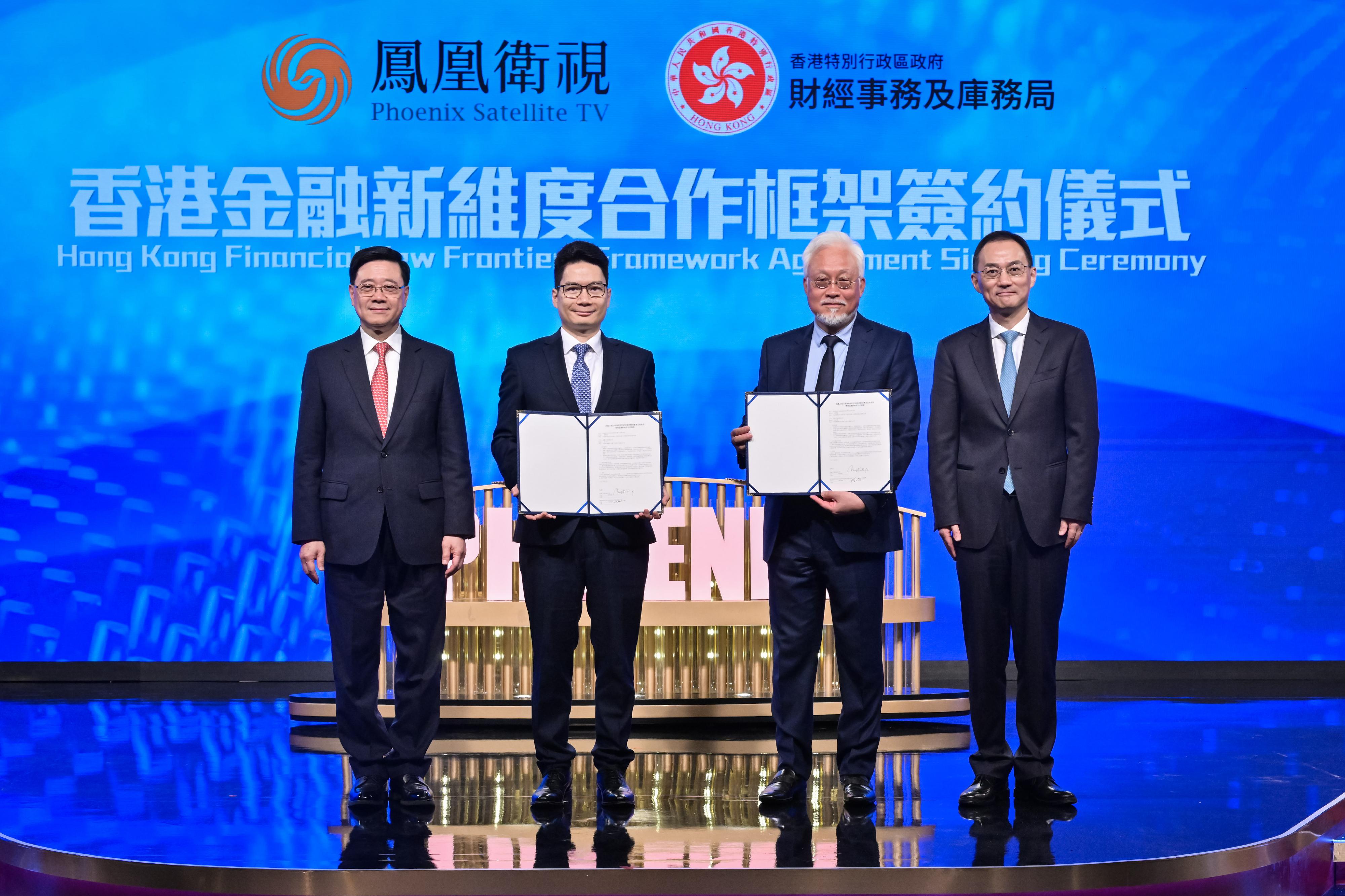 行政長官李家超今日（四月二十二日）出席鳳凰衛視香港台於免費電視85頻道開播一周年慶典。圖示李家超（左一）和鳳凰衛視董事局主席兼行政總裁徐威（右一）見證署理財經事務及庫務局局長陳浩濂（左二）和鳳凰衛視執行副總裁兼集團財務總監楊家強（右二）就有關財經事務及庫務局與鳳凰衛視「香港金融新維度」合作框架展示簽約文本。