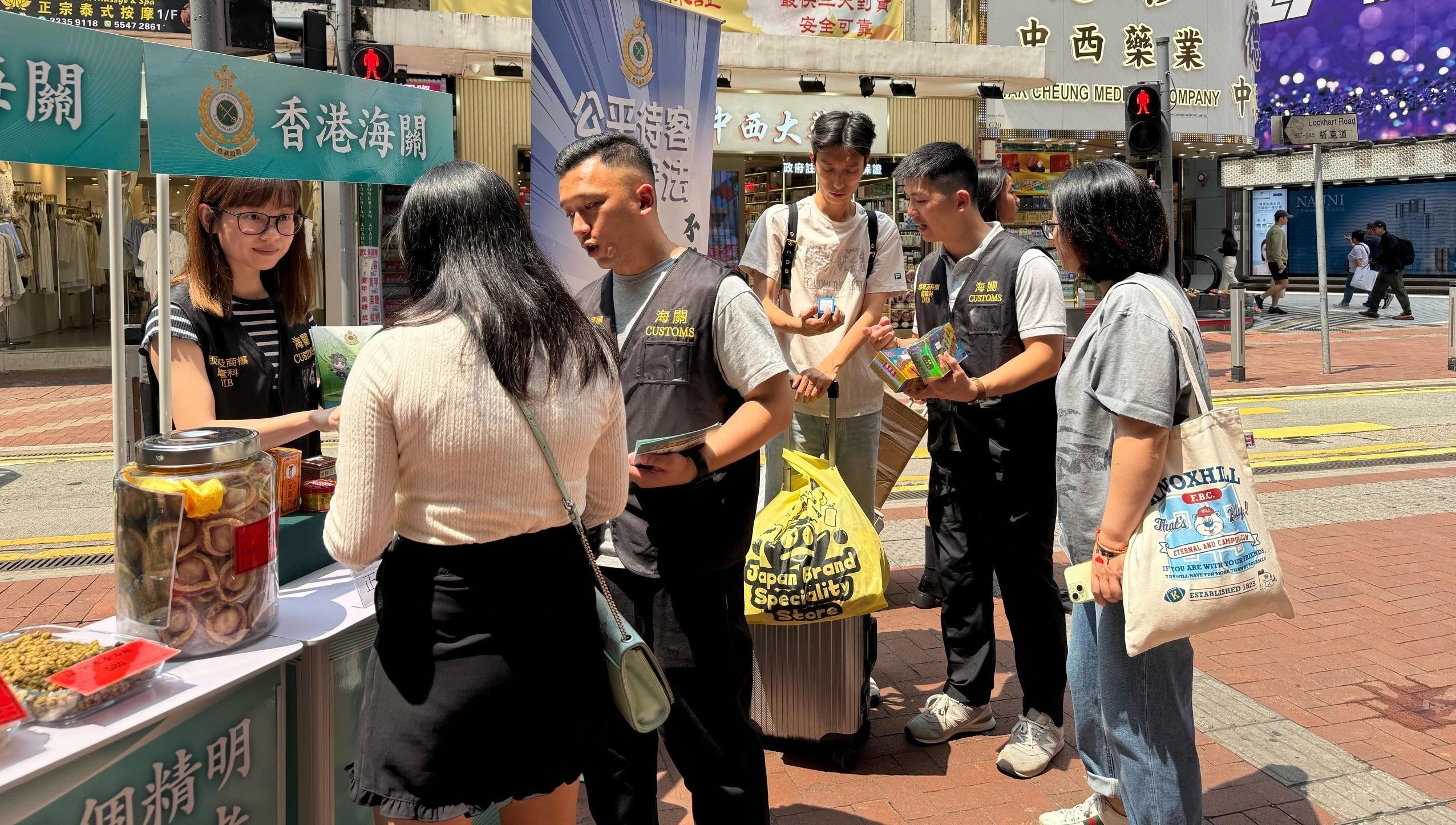 香港海關四月二十四日起展開特別行動，於內地勞動節黃金周期間加強巡查全港各區購物熱點，提醒商戶遵守《商品說明條例》規定，以保障及推廣本地消費者和旅客的權益。圖示海關人員在銅鑼灣進行宣傳教育，並派發宣傳單張。