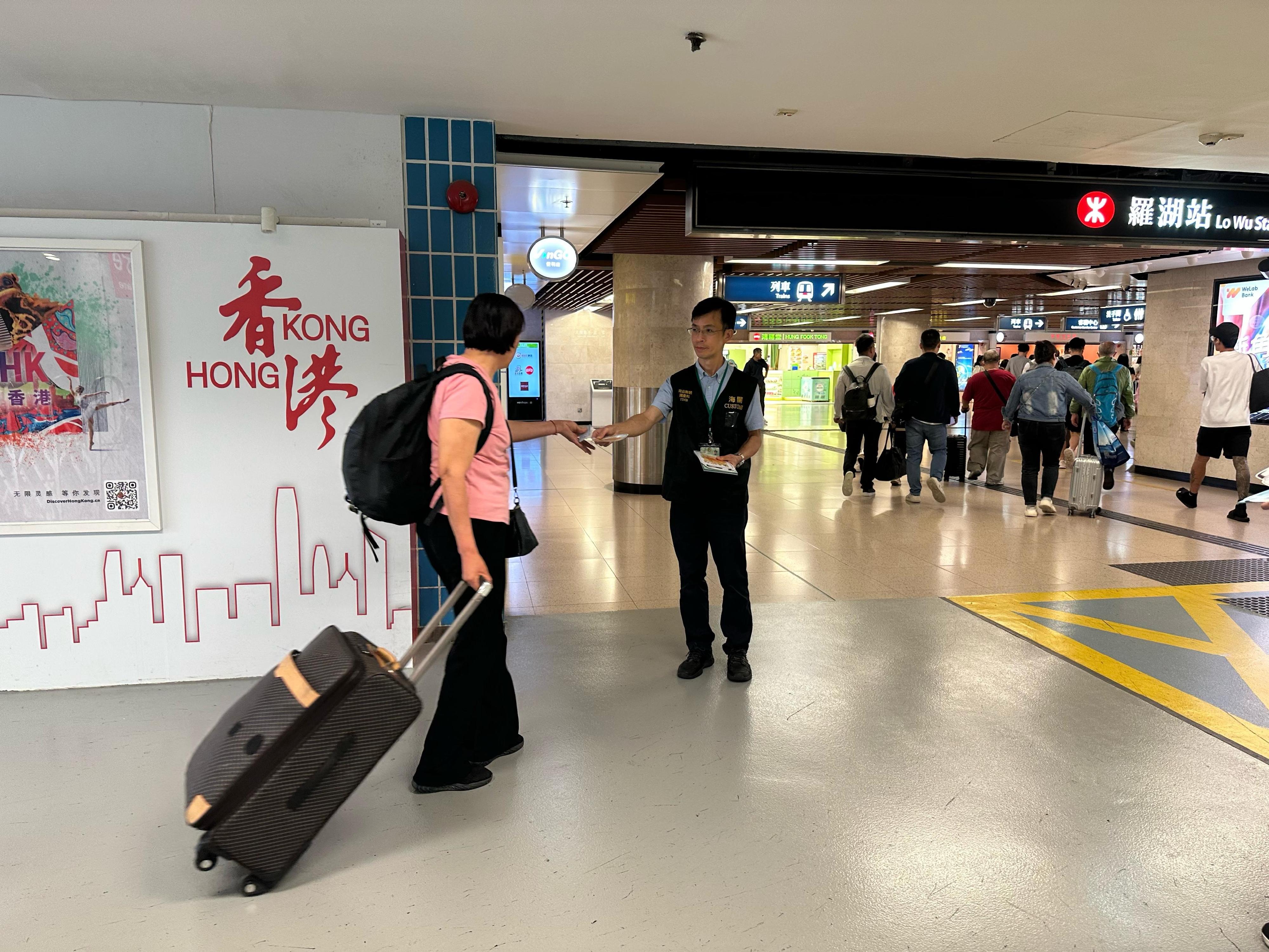 香港海關四月二十四日起展開特別行動，於內地勞動節黃金周期間加強巡查全港各區購物熱點，提醒商戶遵守《商品說明條例》規定，以保障及推廣本地消費者和旅客的權益。圖示海關人員在羅湖口岸派發宣傳單張。