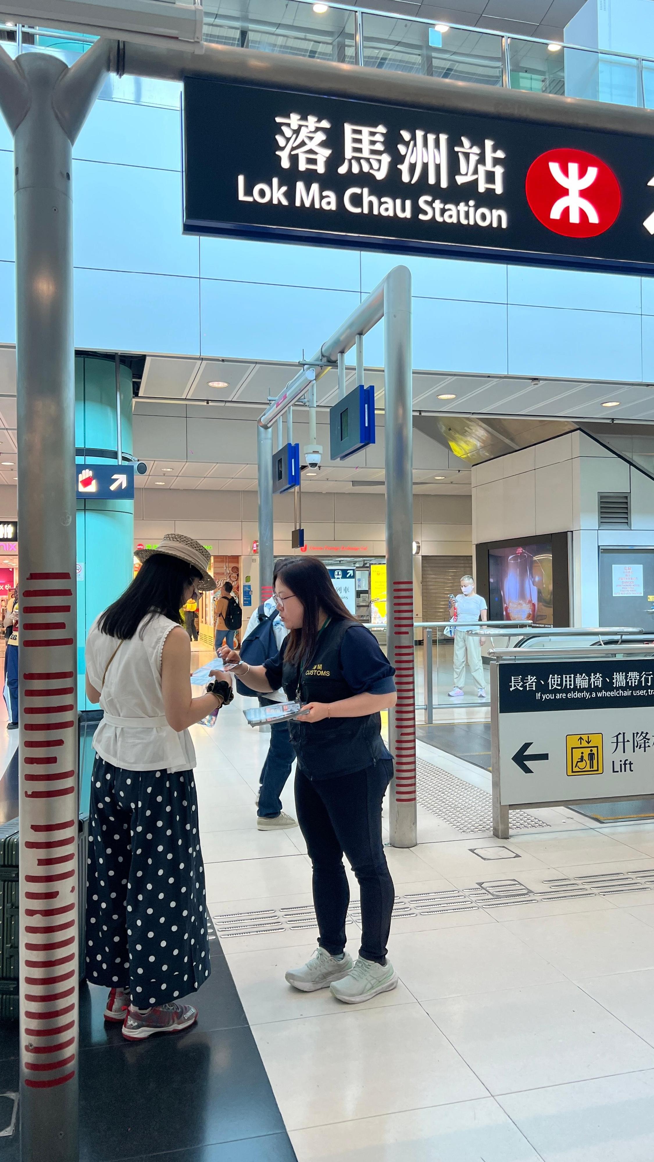 香港海關四月二十四日起展開特別行動，於內地勞動節黃金周期間加強巡查全港各區購物熱點，提醒商戶遵守《商品說明條例》規定，以保障及推廣本地消費者和旅客的權益。圖示海關人員在落馬洲口岸派發宣傳單張。
