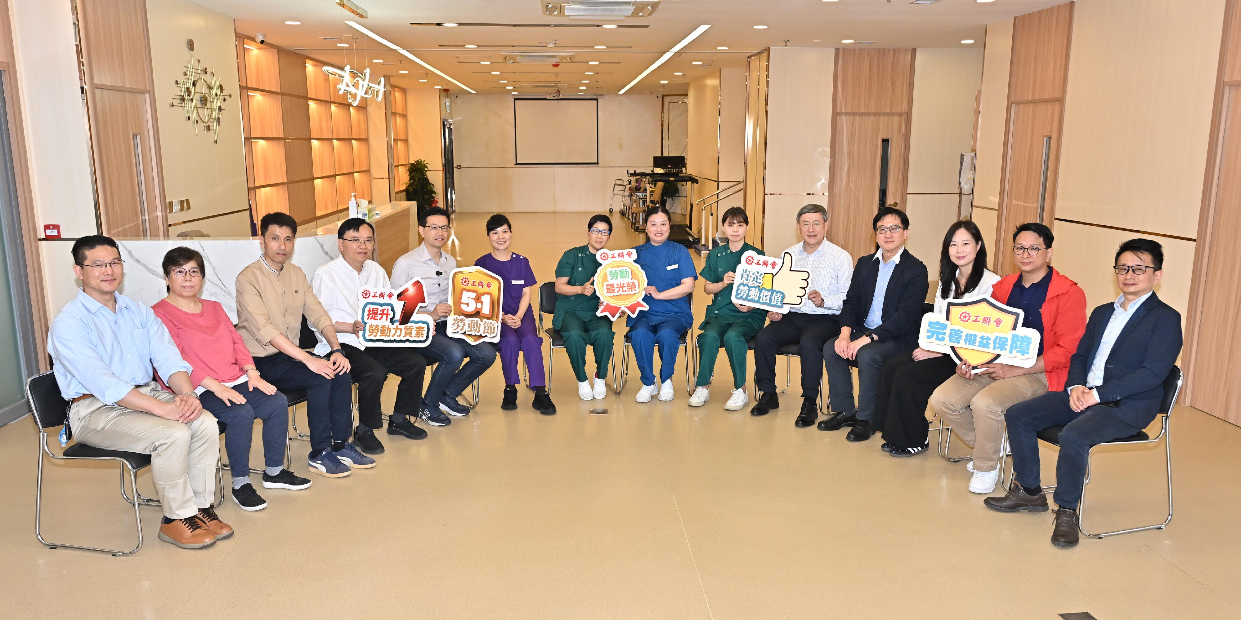 政務司副司長卓永興（右五）今日（五月一日）在將軍澳安老院舍與前線員工合照。同場還有香港工會聯合會（工聯會）會長吳秋北（左五）、工聯會理事長黃國（左四）、立法會議員鄧家彪（右二）和梁子穎（左一）及工聯會副理事長張凱榮（左三）。