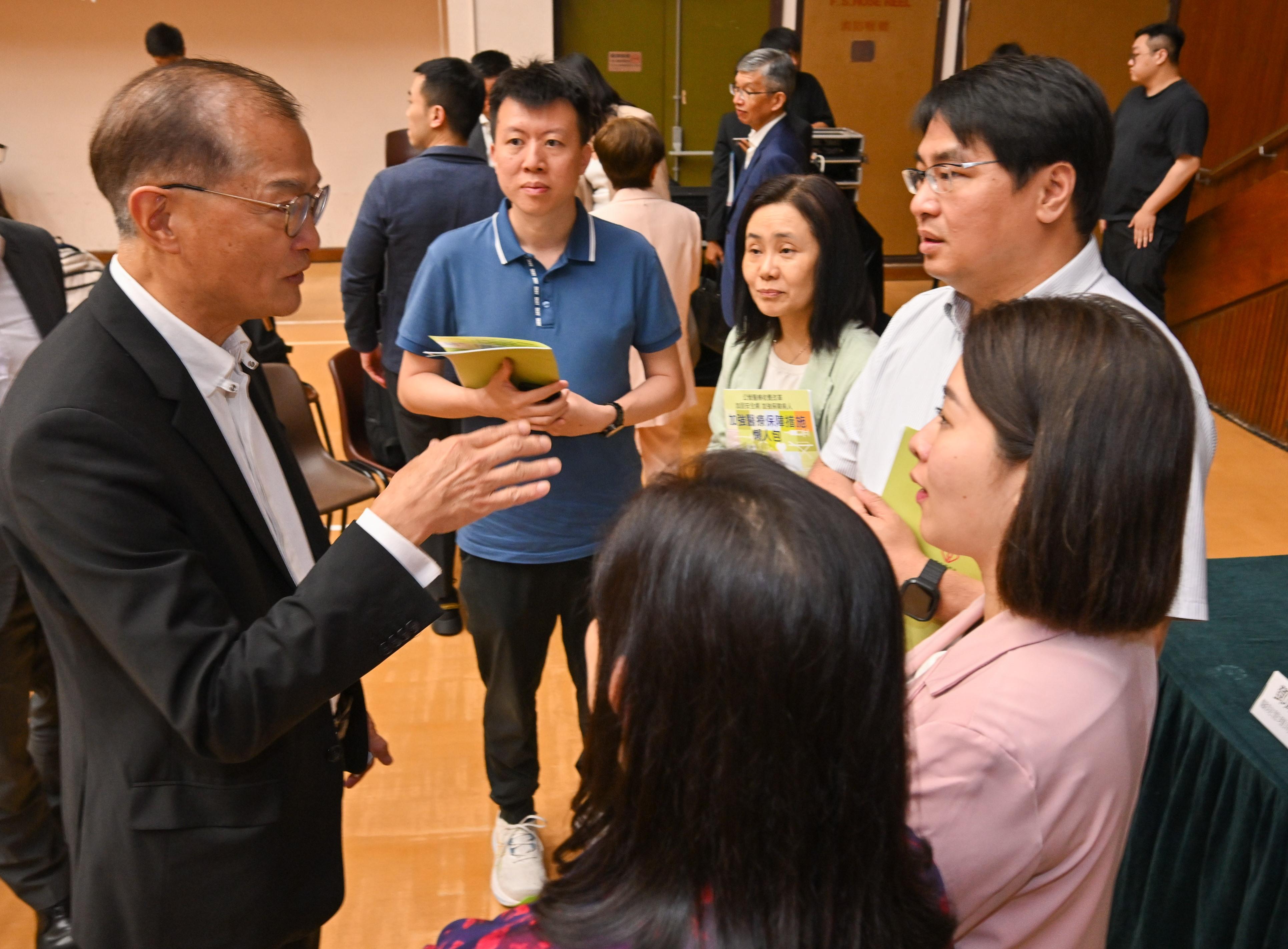 醫務衞生局局長盧寵茂教授（左一）今日（五月九日）出席第二場公營醫療收費改革區議會簡介會，向參加者講解改革內容。
