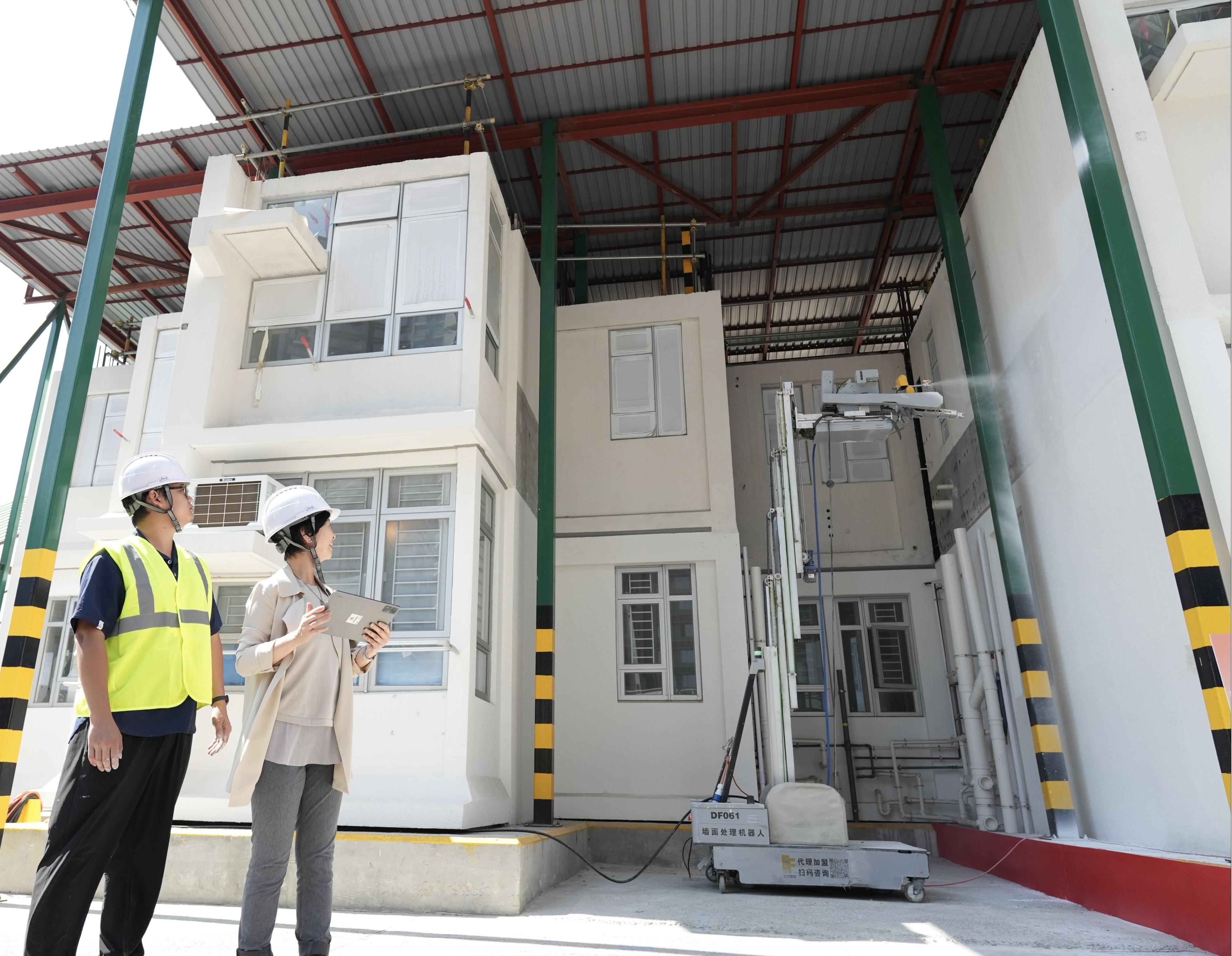 房屋局今日（五月十二日）舉辦「房屋建築機械人——油漆大師比拼賽x武林大會」，以促進行業技術落地，帶領公營房屋發展邁入智能建造新紀元。圖示房屋局局長何永賢（右）示範操作六米高三合一牆面處理機械人。