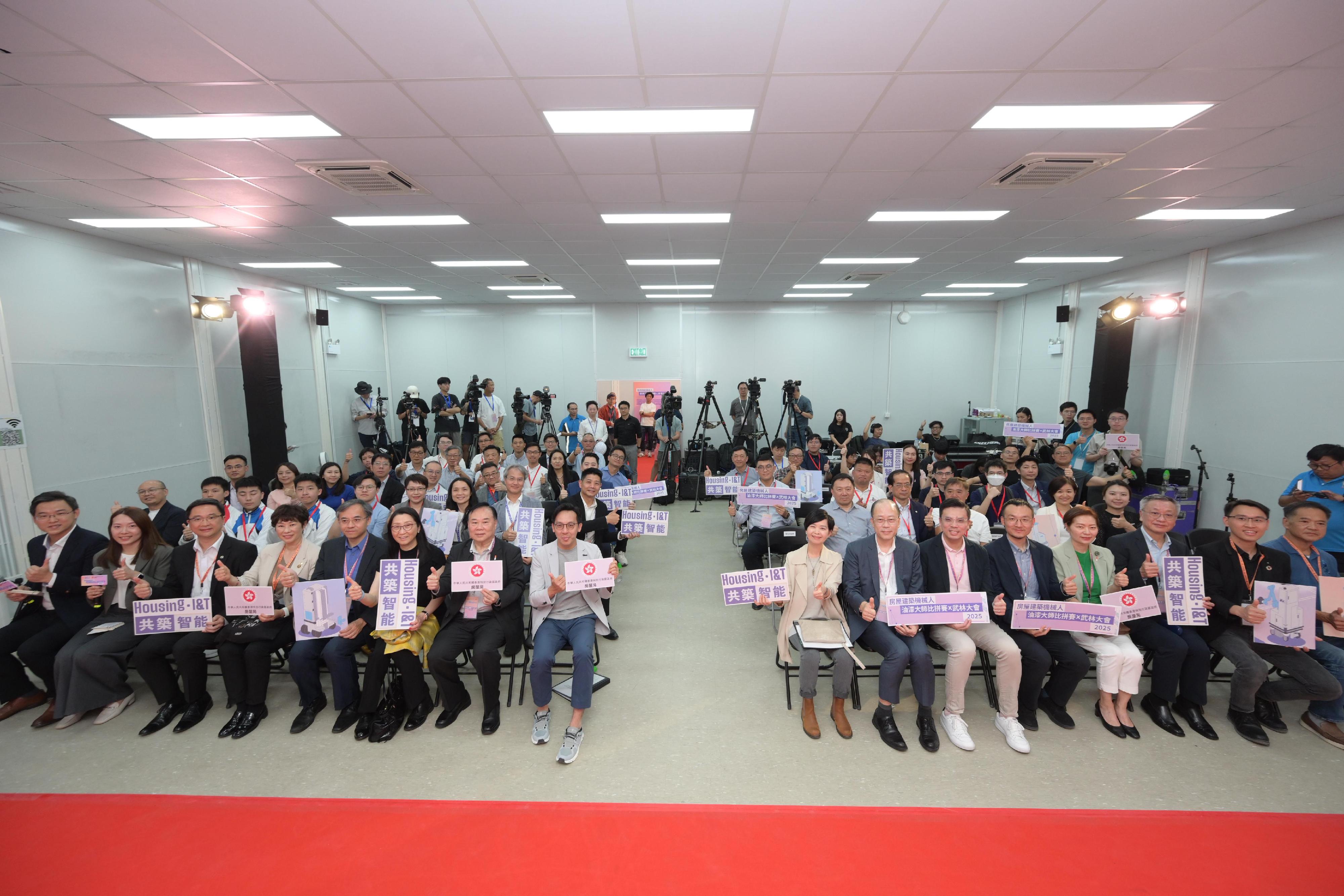 房屋局今日（五月十二日）舉辦「房屋建築機械人——油漆大師比拼賽x武林大會」，以促進行業技術落地，帶領公營房屋發展邁入智能建造新紀元。圖示房屋局局長何永賢（前排右八）、房屋署副署長（發展及建築）梁洪偉（前排左八）與其他嘉賓合照。