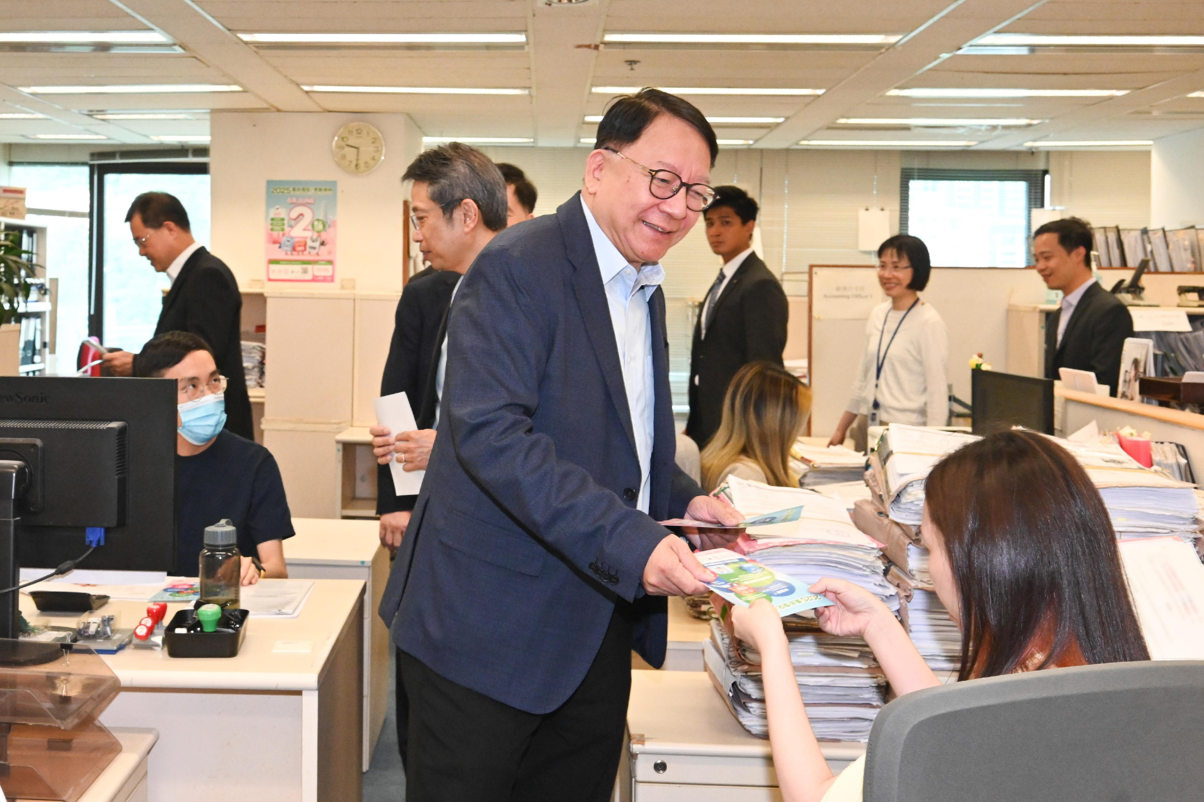 政務司司長陳國基今日（五月十三日）聯同四個公務員中央評議會的代表，一起到位於金鐘政府合署的多個樓層，呼籲同事積極登記成為選民，並在今年十二月七日舉行的立法會換屆選舉踴躍投票，履行公民責任。圖示陳國基（中）在法律援助署同事的工作間向他們派發宣傳單張，呼籲同事積極登記成為選民。