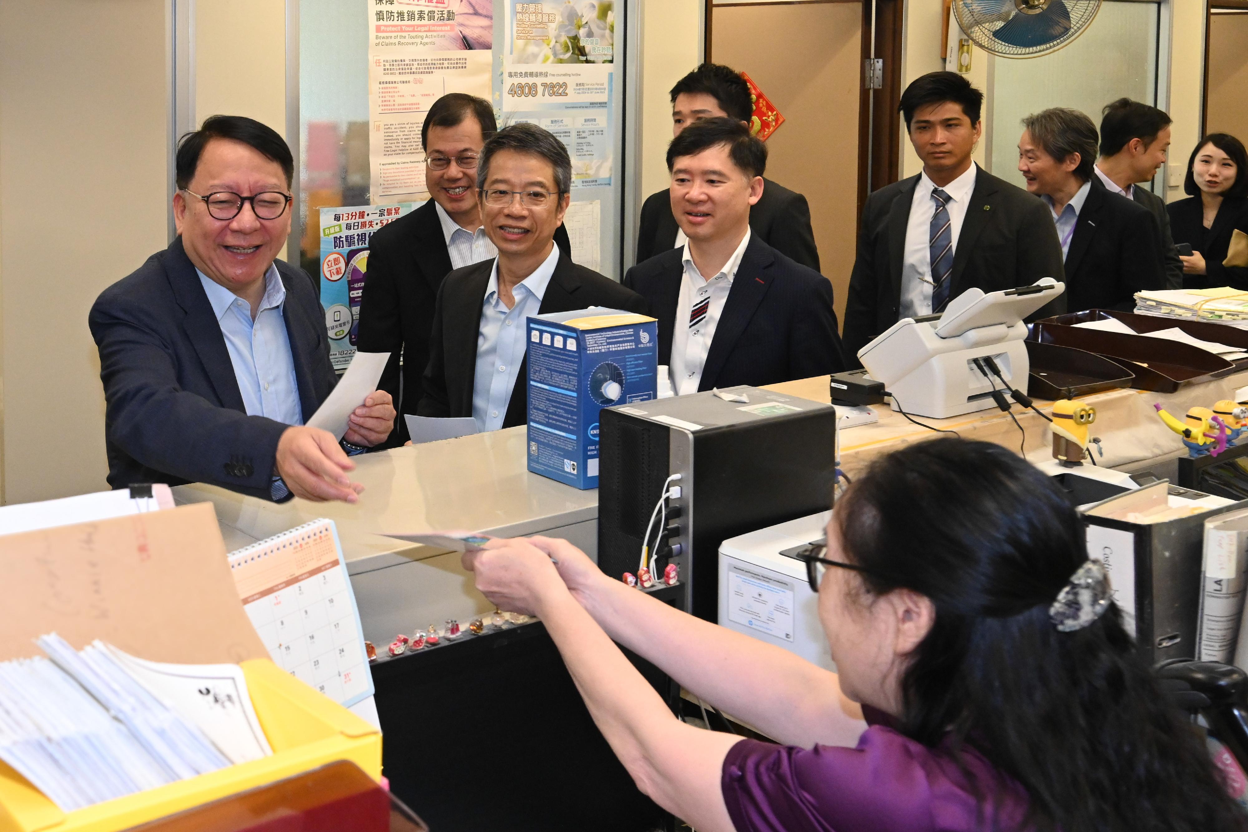 政務司司長陳國基今日（五月十三日）聯同四個公務員中央評議會的代表，一起到位於金鐘政府合署的多個樓層，呼籲同事積極登記成為選民，並在今年十二月七日舉行的立法會換屆選舉踴躍投票，履行公民責任。圖示陳國基（左一）在法律援助署同事的工作間向他們派發宣傳單張，呼籲同事積極登記成為選民。旁為署理政制及內地事務局局長胡健民（左四）、公務員事務局常任秘書長梁卓文（左三）和法律援助署署長莊因東（左二）。
