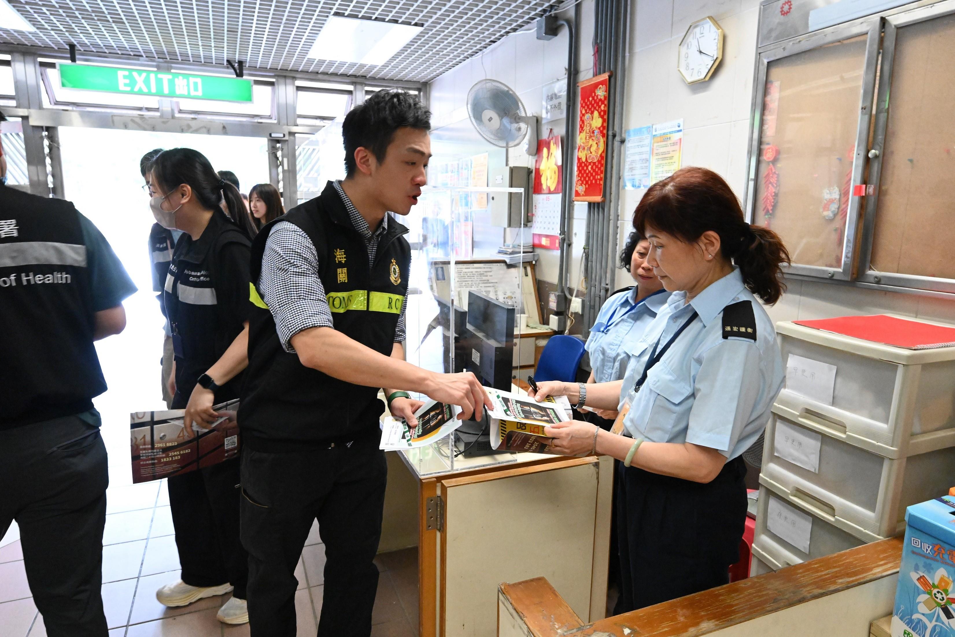Hong Kong Customs conducted a joint anti-illicit cigarette publicity campaign with members of the Kwai Tsing District Council, the Tobacco and Alcohol Control Office of the Department of Health and the Housing Department at Cheung Hong Estate and Cheung Ching Estate in Tsing Yi today (May 15). Photo shows a Customs officer promoting anti-illicit cigarette messages to an estate security personnel.
