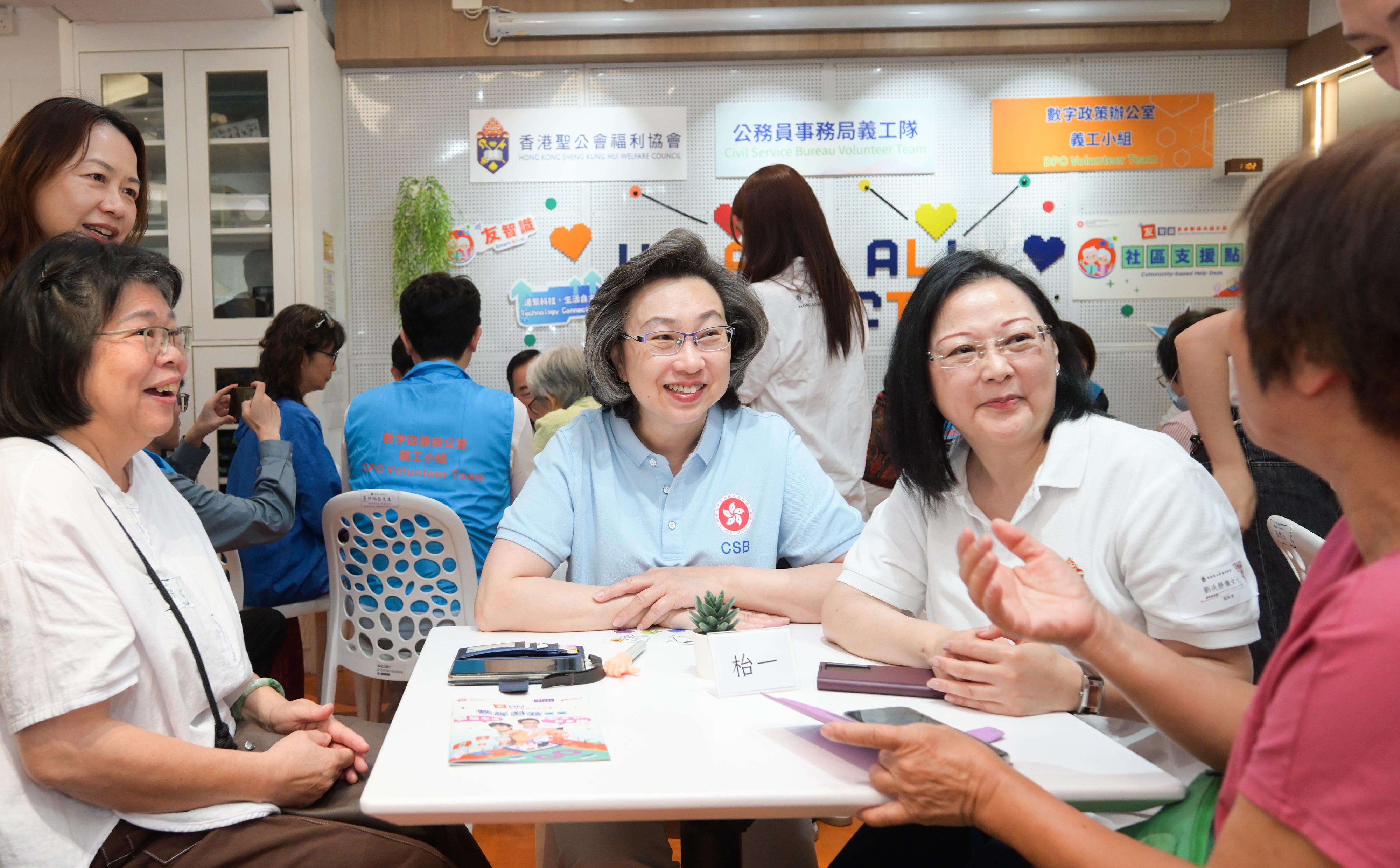 公務員事務局義工隊及數字政策辦公室義工小組今日（五月十七日）攜手到位於土瓜灣的香港聖公會樂民郭鳳軒綜合服務中心，進行「友智識」長者數碼共融計劃義工活動，輔助長者學習使用智能電話及應用程式，並一起互動體驗樂齡科技的樂趣，將科技融入日常生活之中。圖示公務員事務局局長楊何蓓茵（右三）和香港聖公會福利協會總幹事劉冼靜儀（右二）解答長者對使用智能電話的疑問。