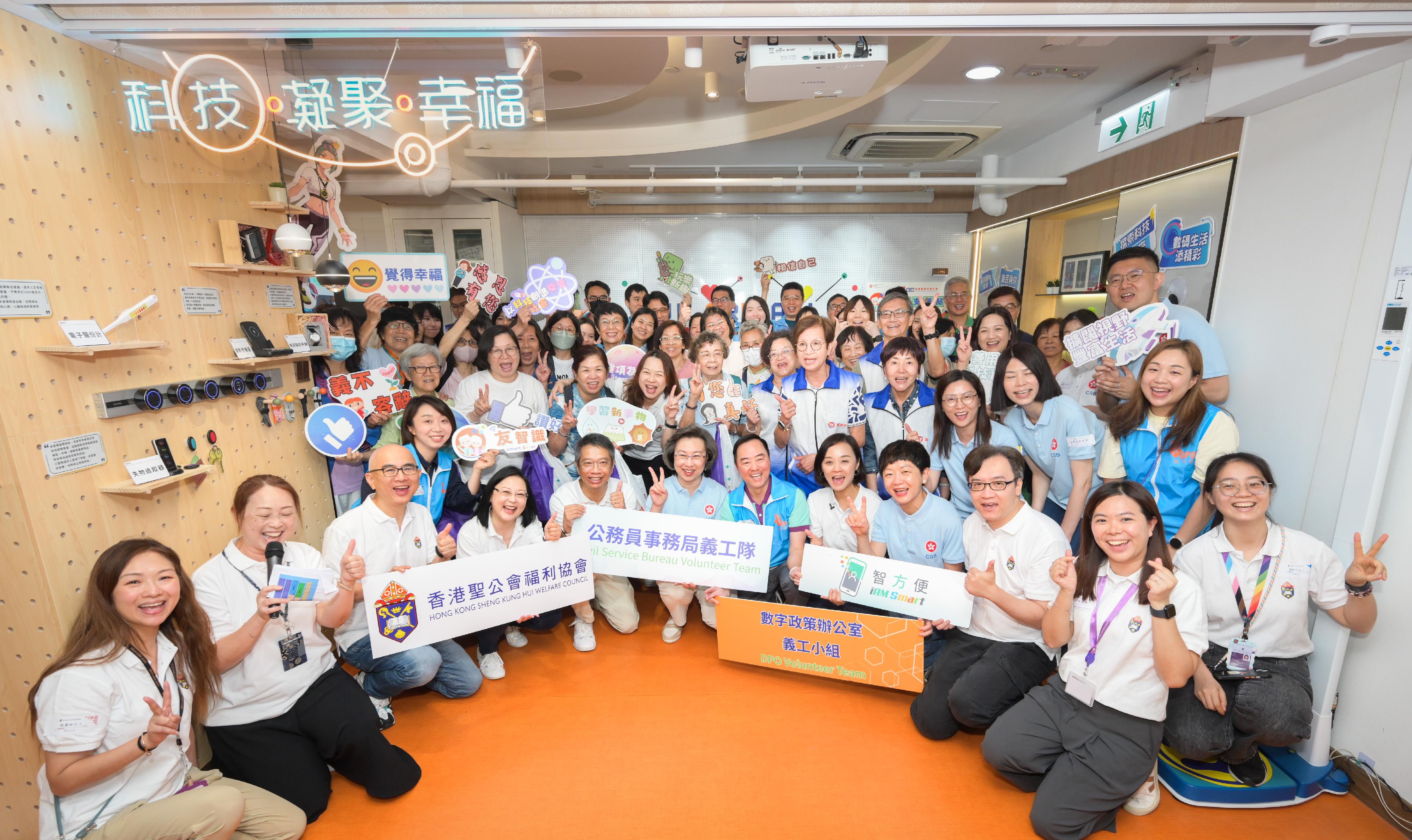 公務員事務局義工隊及數字政策辦公室義工小組今日（五月十七日）攜手到位於土瓜灣的香港聖公會樂民郭鳳軒綜合服務中心，進行「友智識」長者數碼共融計劃義工活動，輔助長者學習使用智能電話及應用程式，並一起互動體驗樂齡科技的樂趣，將科技融入日常生活之中。公務員事務局局長楊何蓓茵（前排左六）、公務員事務局常任秘書長梁卓文（前排左五）、數字政策專員黃志光（前排左七），以及香港聖公會福利協會總幹事劉冼靜儀（前排左四），與公務員義工及參與活動的長者合照。