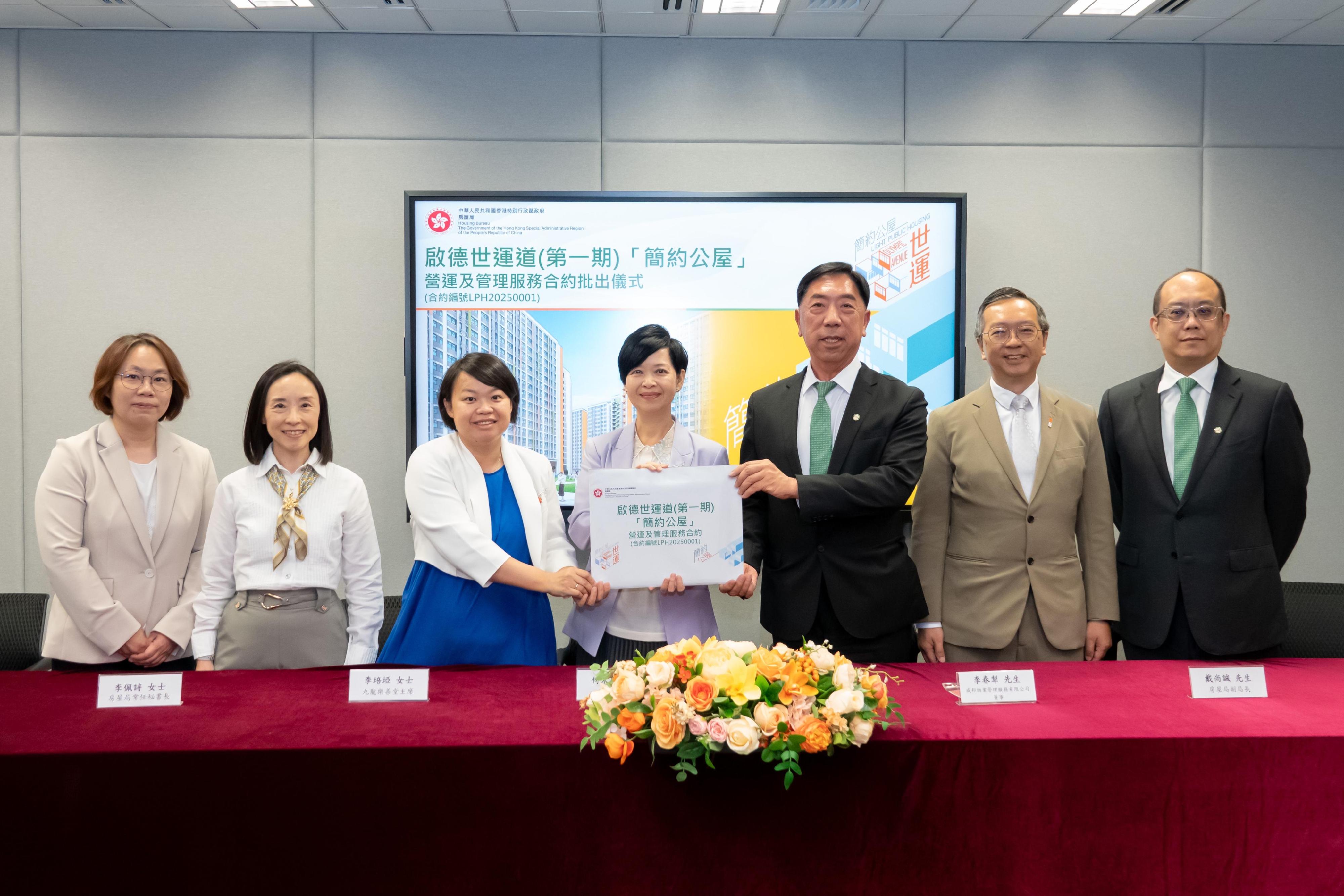 房屋局今日（五月二十六日）批出兩份「簡約公屋」項目的營運及管理服務合約。圖示房屋局局長何永賢（中）、房屋局常任秘書長李佩詩（左二）及房屋局副局長戴尚誠（右二）在批出合約的儀式上，與啟德世運道第一期「簡約公屋」項目營運及管理服務合約（合約編號LPH20250001）的中標機構九龍樂善堂——威邦物業管理服務有限公司聯營代表合照。