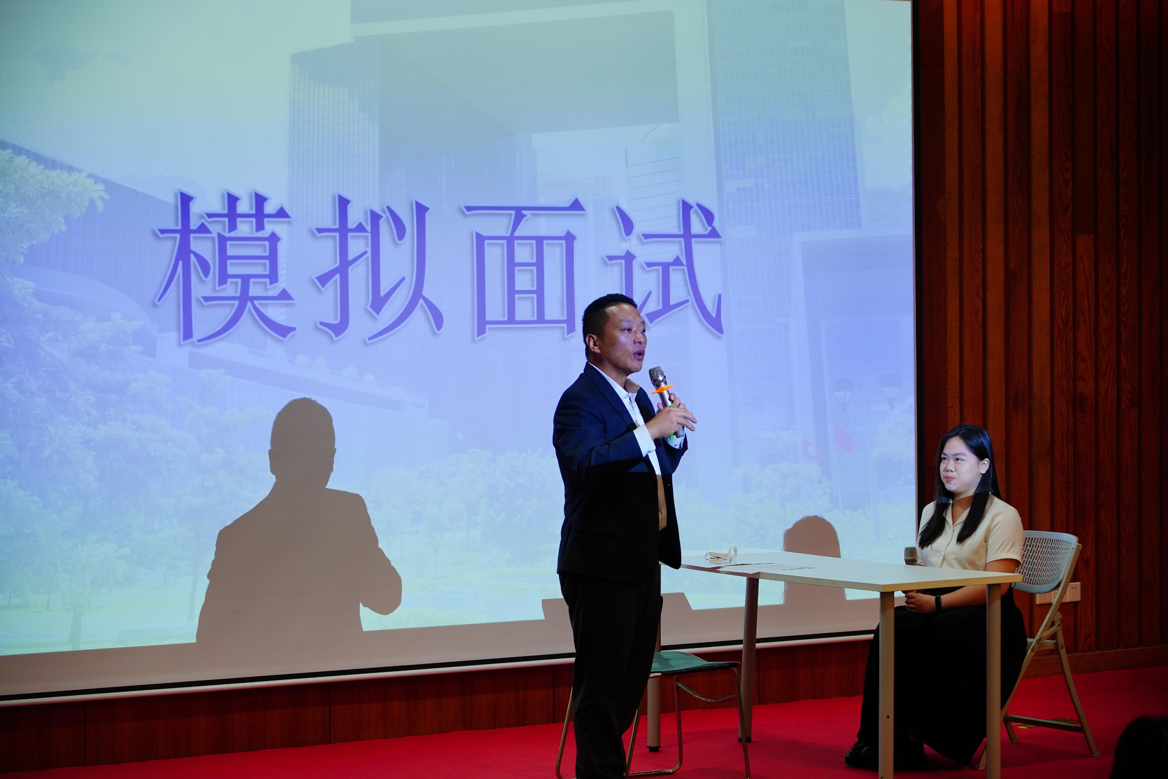 The Civil Service Bureau, together with representatives from the Civil Aviation Department (CAD), the Home Affairs Department and the Digital Policy Office, are visiting Guangzhou and Wuhan to conduct career talks at Sun Yat-sen University, Jinan University, Wuhan University and Huazhong University of Science and Technology for four consecutive days starting today (May 27), to provide Hong Kong students studying on the Mainland with information on various positions in the Hong Kong Special Administrative Region Government. Photo shows CAD Training Officer Mr Ronald Shing (left) conducting a mock interview for the Student Air Traffic Control Officer position with a Hong Kong student at the career talk at Sun Yat-sen University today to let the student experience and other students to observe the interview process.